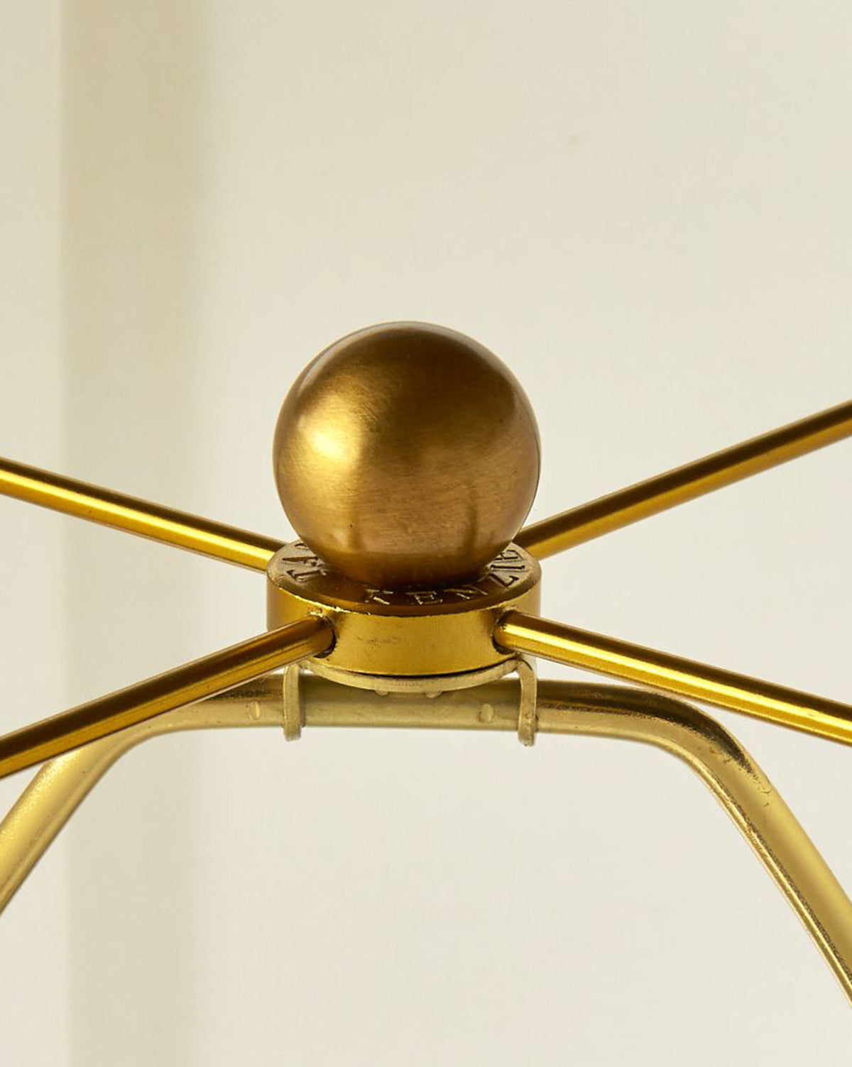 Close-up of the Dynasty Table Lamp’s metallic gold harp with a round finial on top, set against a plain background. The harp arms extend outward from the lamp’s central fixture, by McGee & Co.
