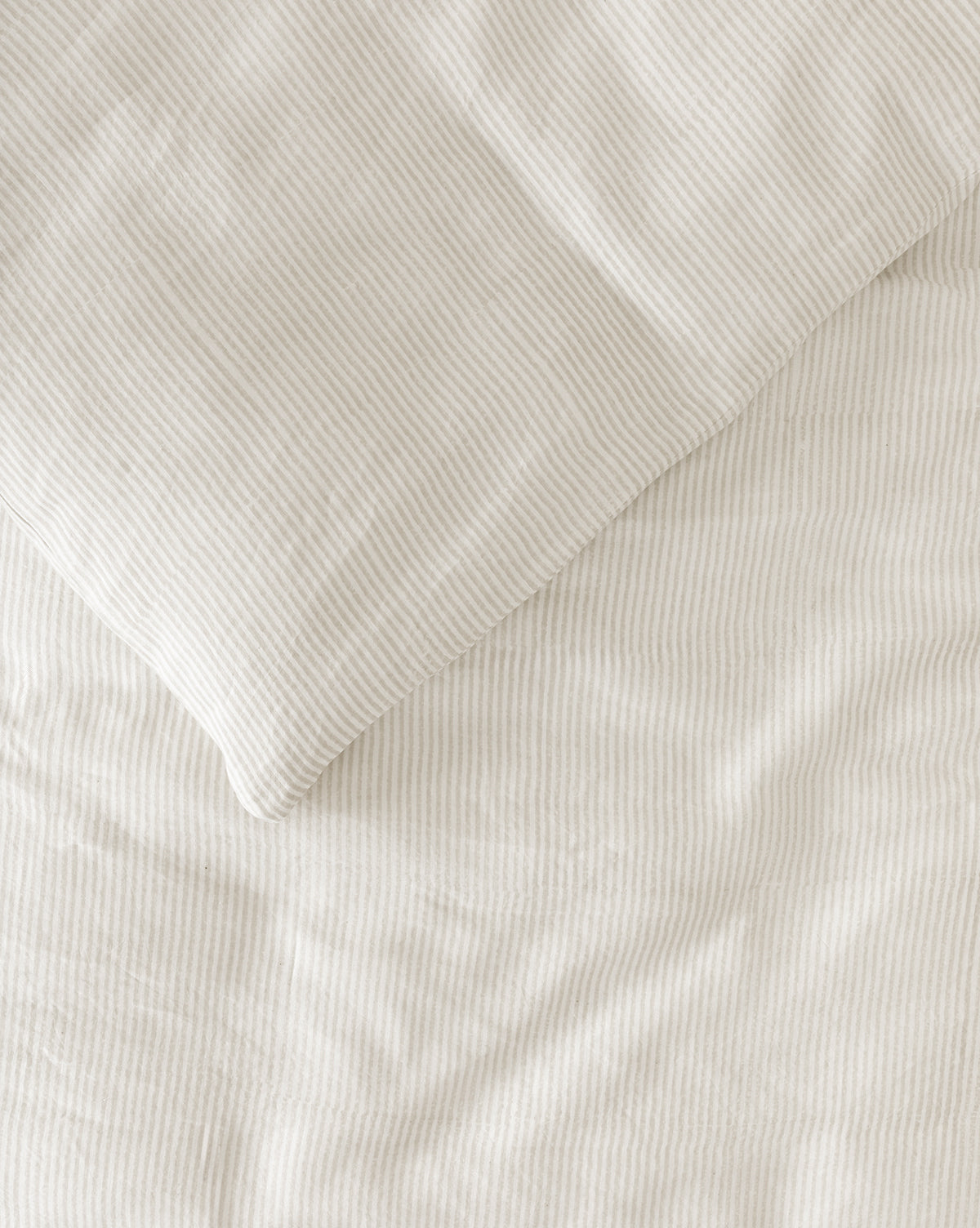 A close-up view of the Easton Striped Duvet Cover in cream and oatmeal, featuring subtle vertical pinstripes on soft, textured fabric—perfect for adding elegance to your bedding ensemble.