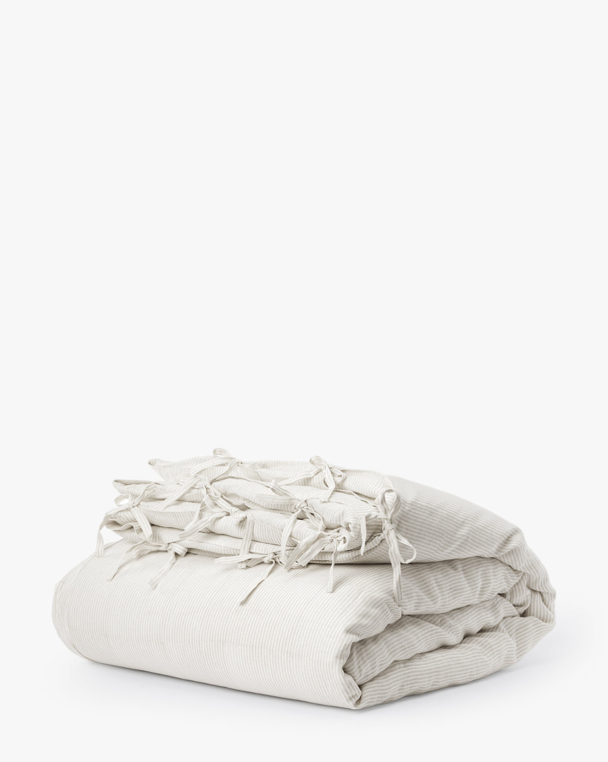 The Easton Striped Duvet Cover, in folded cream and oatmeal with subtle stripes and multiple tied bows along the edge, is displayed on a white background.