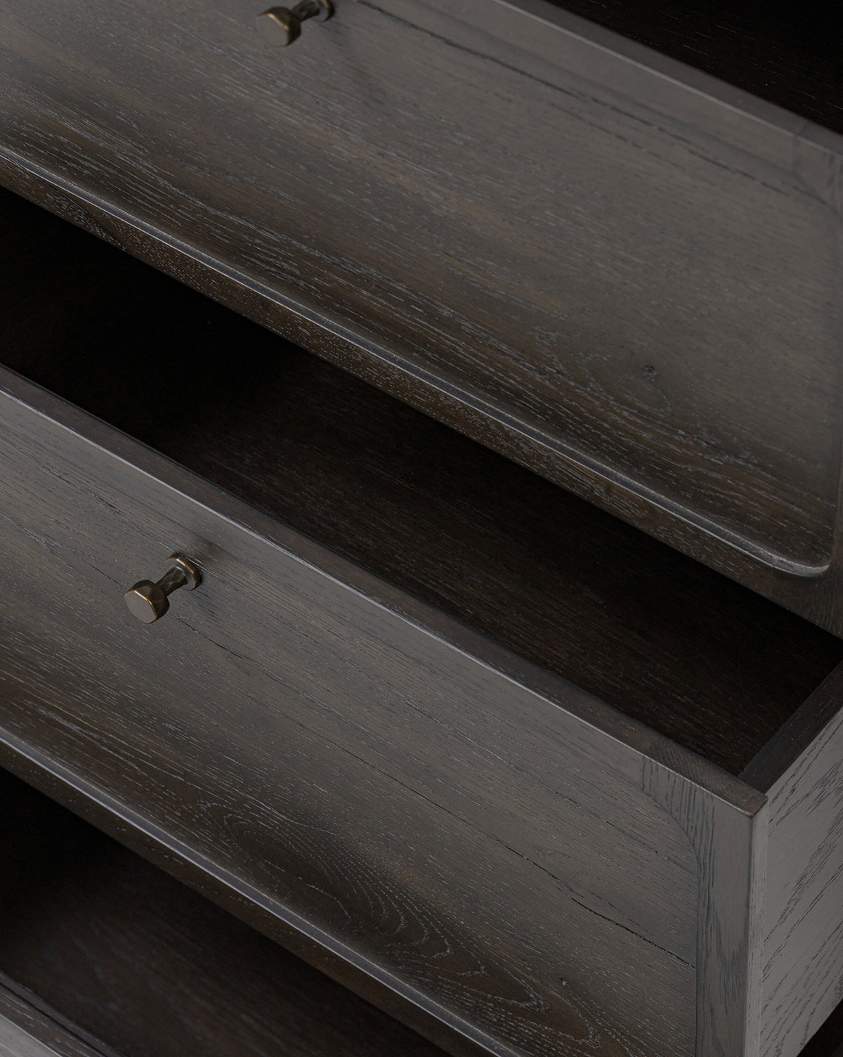Two dark wood drawers of the Eldoria Oak Sideboard, featuring metallic knobs and visible grain on the fronts and sides, are partly open to show their empty interiors, showcasing its modern deco style, by McGee & Co.