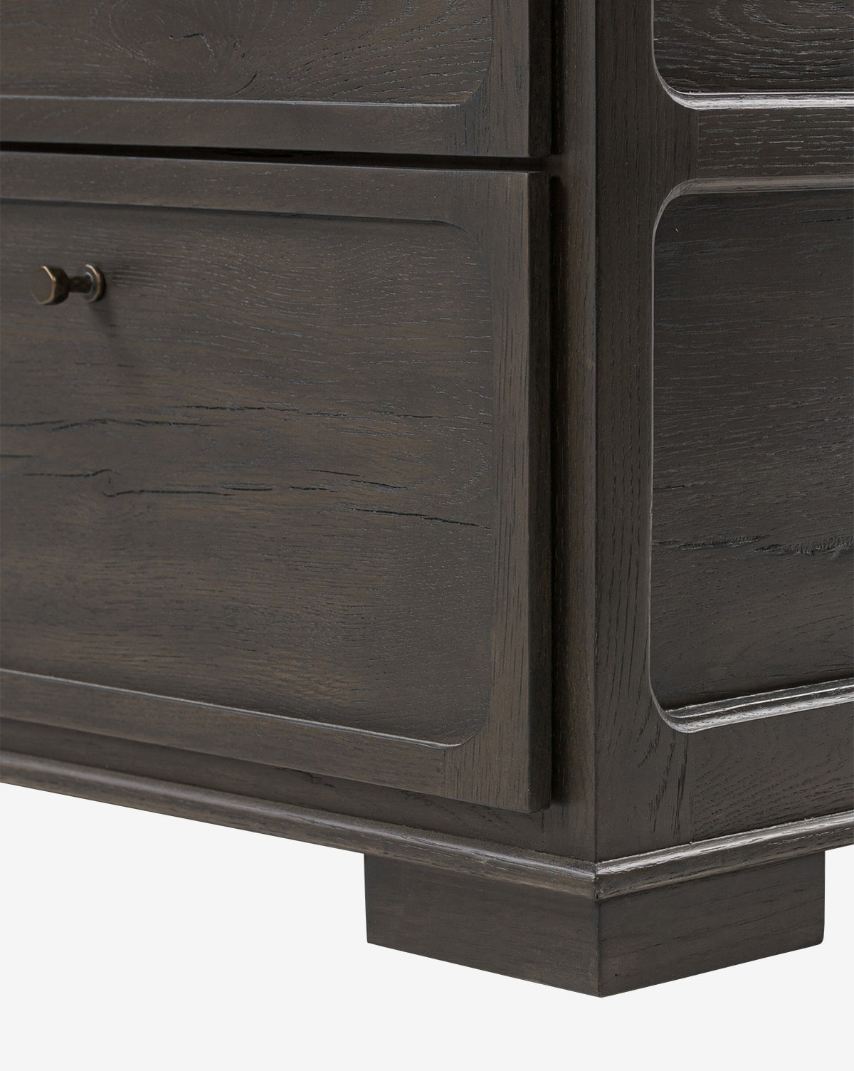 Close-up of the lower corner of the Eldoria Oak Sideboard, showcasing its black oak finish, visible wood grain, two drawers with small round knobs, and flat rectangular legs—perfect for a modern deco look, by McGee & Co.