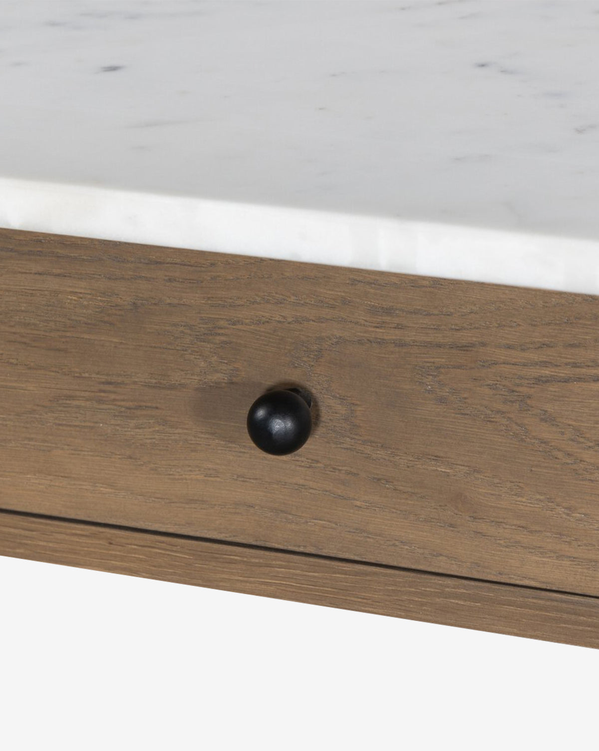 Close-up of the Eldric Kitchen Island’s wooden drawer with a small round black knob, beneath a white marble tabletop and solid oak base, by McGee & Co.