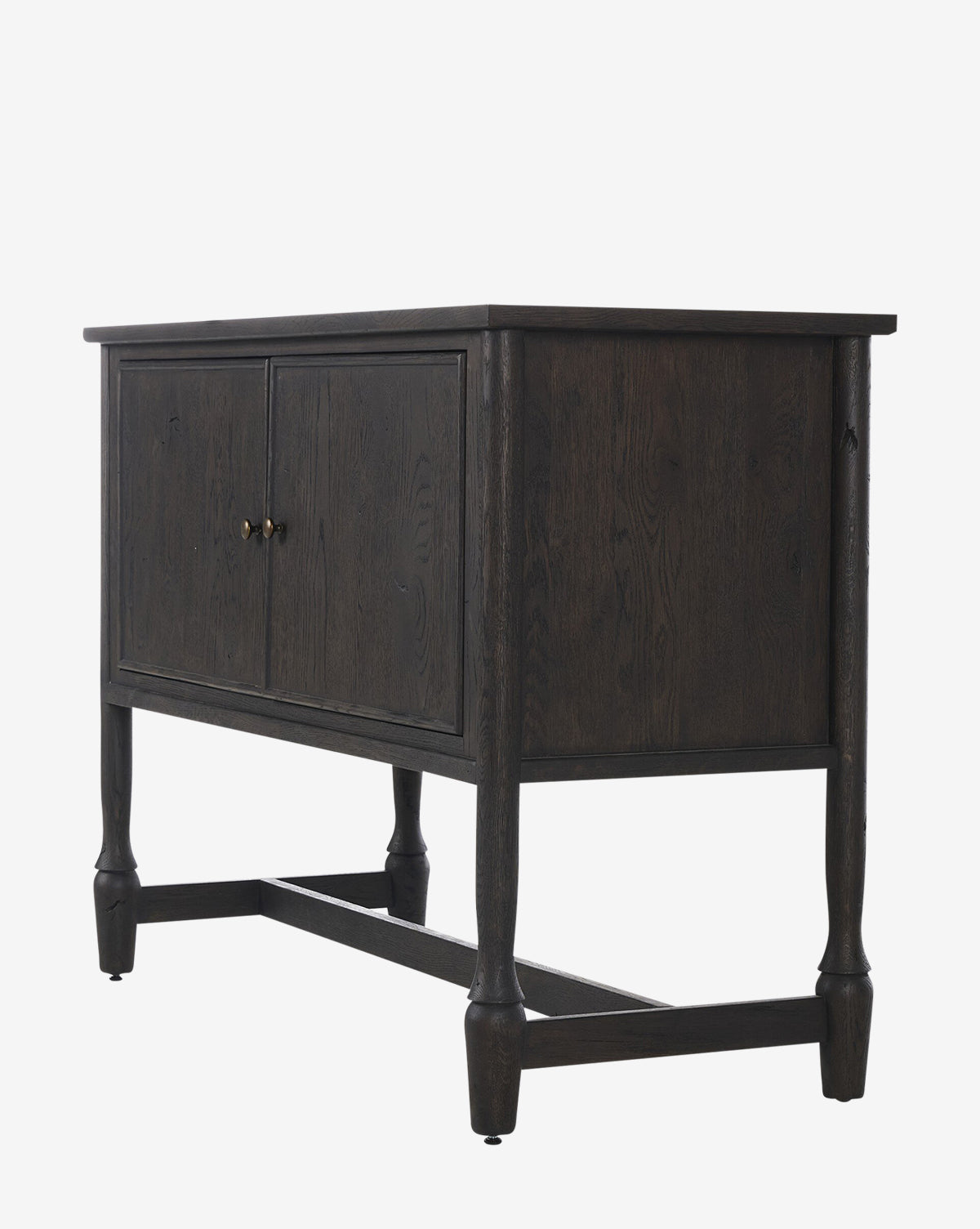 The Elmer Sideboard is a modern piece crafted from solid oak with a cracked smoked black veneer, two front doors with brass knobs, and four legs with horizontal supports, shown against a plain white background by McGee & Co.