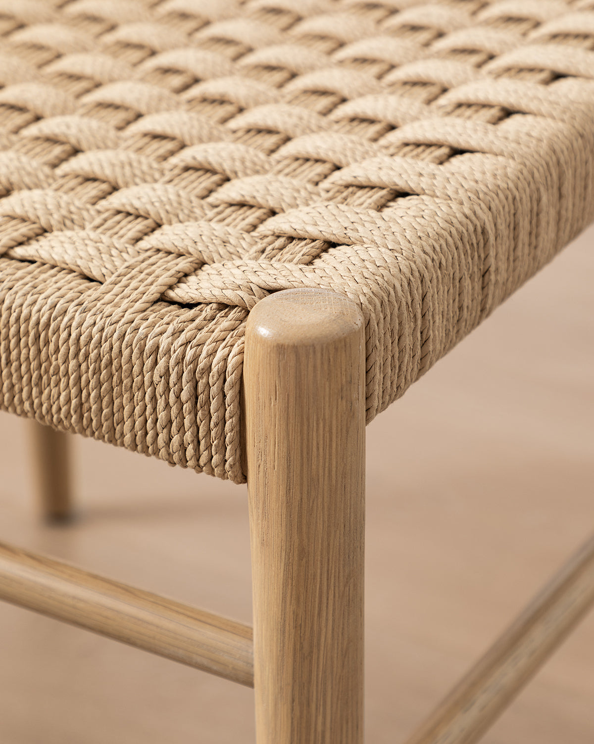 Close-up of the Eloise Woven Chair’s light tan rope seat, tightly crisscrossed over a light wood frame. The detailed craftsmanship reflects classic Danish design, making it an ideal addition to any dining room by McGee & Co.