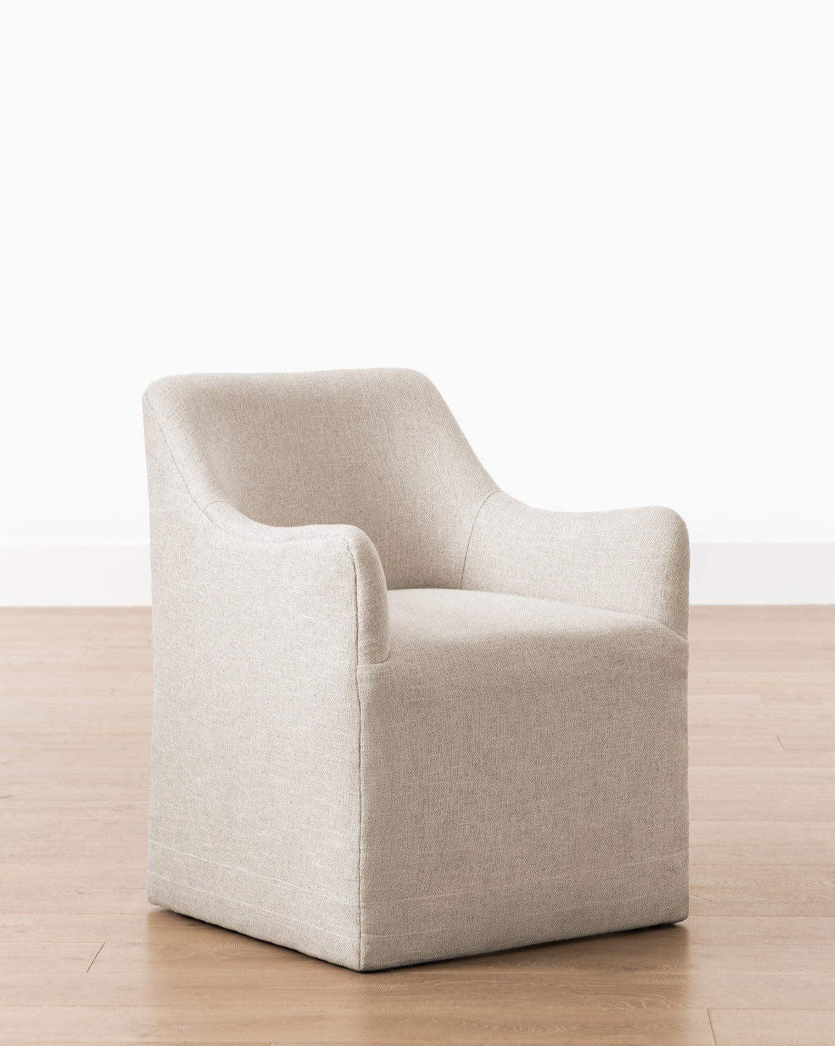 The Elton Dining Chair features light beige linen-blend upholstery, a boxy base, and curved armrests, making it a modern addition to stylish dining spaces by McGee & Co.