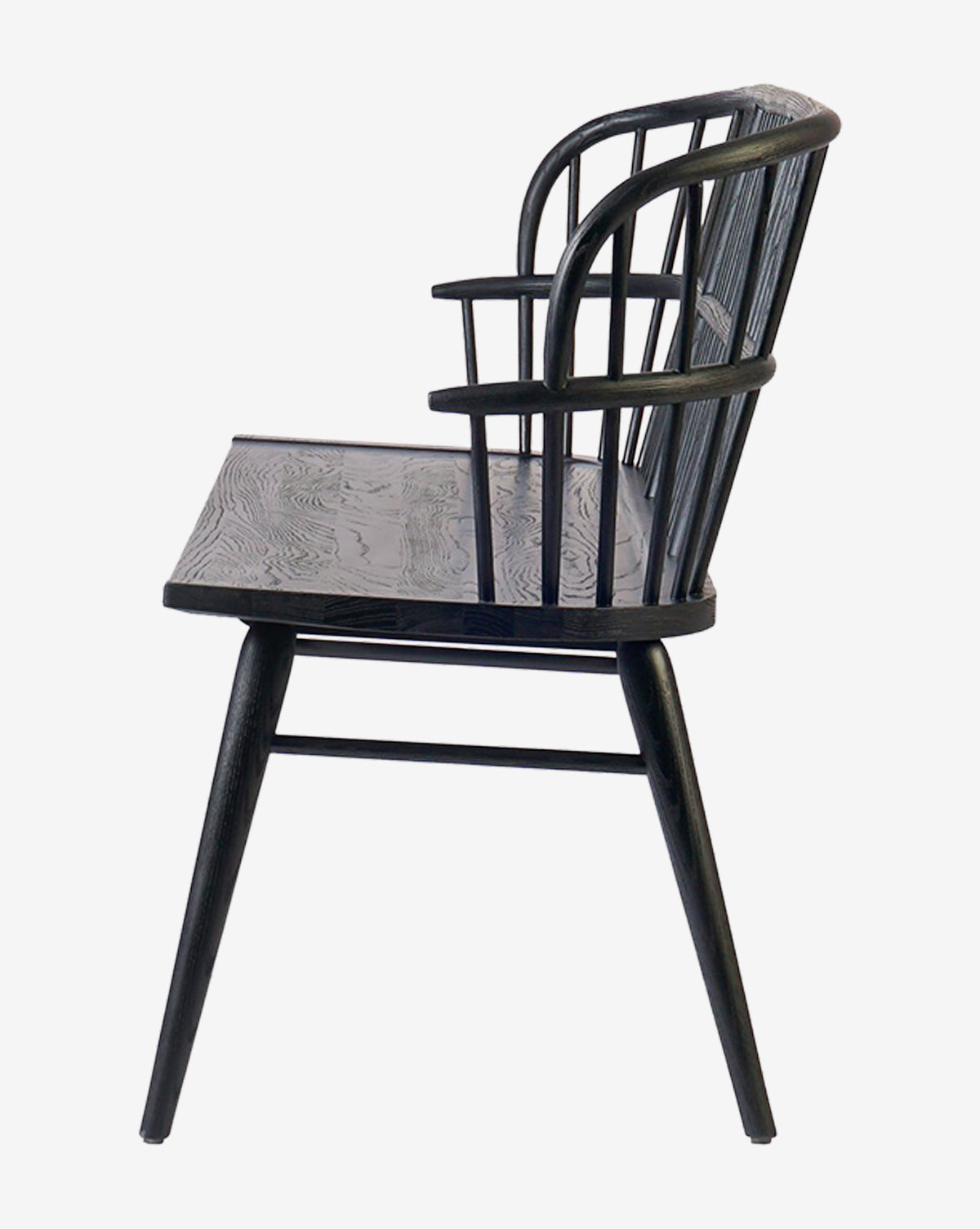 Side view of a black wooden chair with a curved spindle backrest, armrests, angled legs, and visible wood grain texture. Its simple, modern design complements the Elysia Bench’s solid ash frame, by McGee & Co.