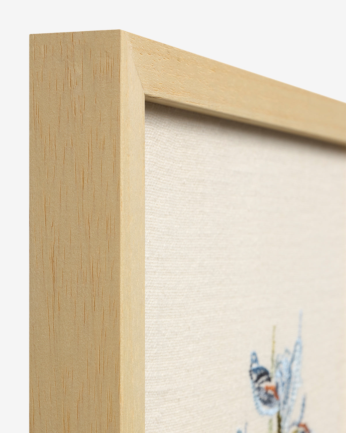 Close-up of a light wood frame with canvas, showcasing Embroidered Blue Iris—cotton embroidery of a blue and orange butterfly on cream, an elegant touch for your botanical wall art collection, by McGee & Co.