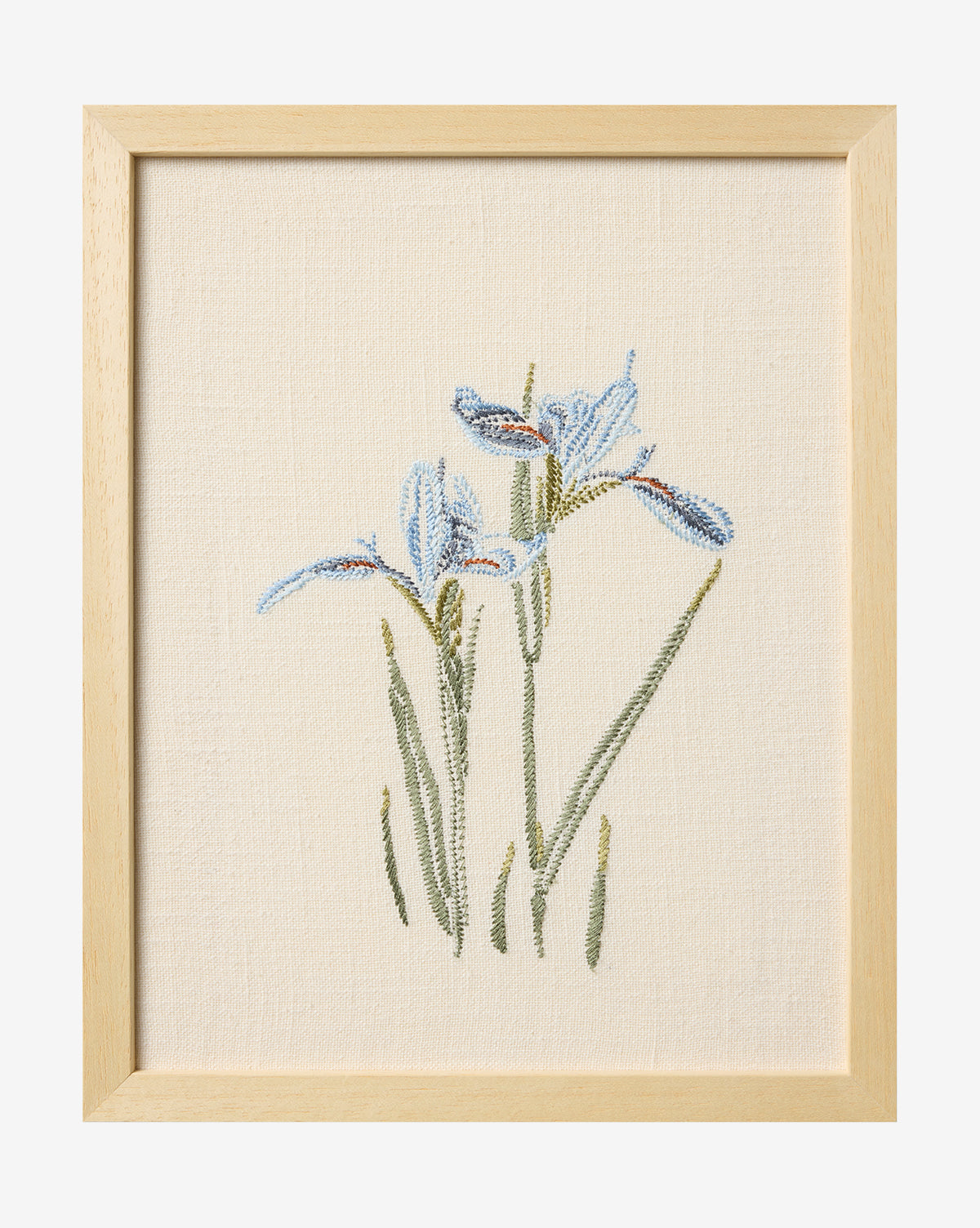The Embroidered Blue Iris is a framed cotton artwork showcasing detailed blue irises with green stems on a cream fabric background—a gorgeous piece of botanical wall art, by McGee & Co.