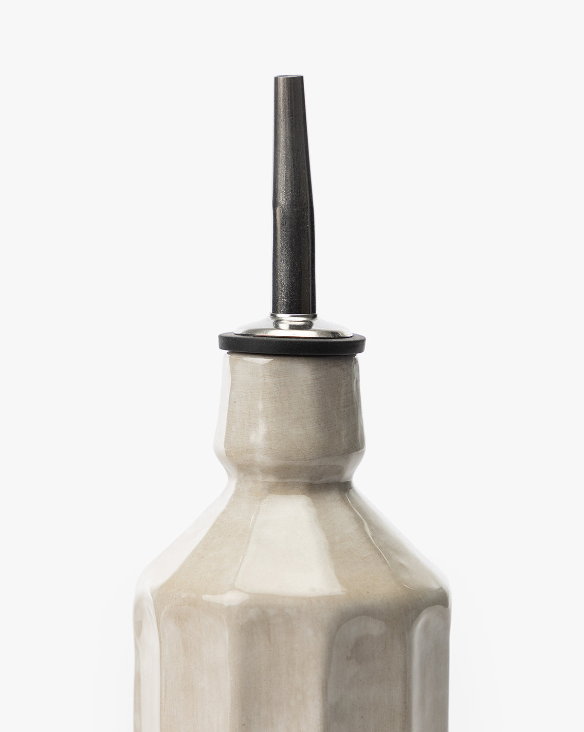 A close-up of the Emilia Cruet, a gray stoneware dispenser with faceted sides and a shiny metal spout, ideal for oil or vinegar, set against a plain white background.
