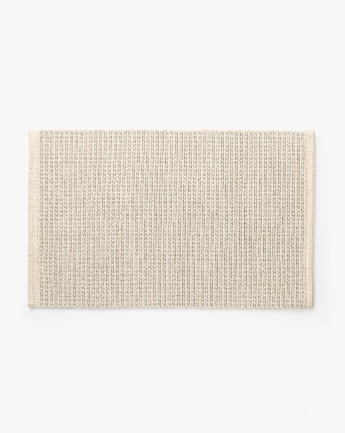 The Emina Bath Mat, a rectangular beige mat made from 100% cotton with a waffle-weave texture and finished edges, is laid flat on a white background—a stylish touch for your bathroom decor.