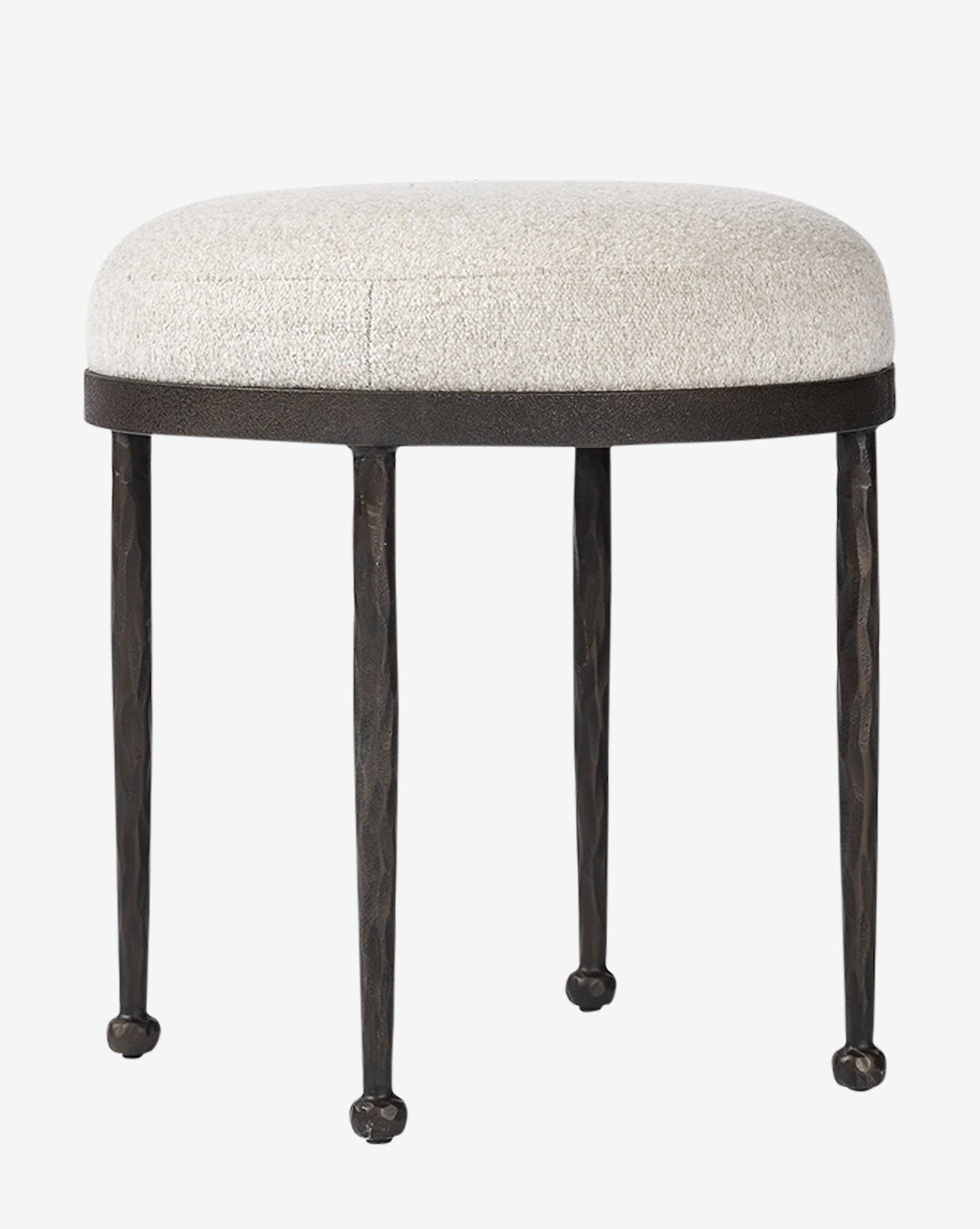 The Emmett Stool by Four Hands features a small hammered bronze frame, a round light cushioned seat, and slender black metal legs with rounded feet—an ideal accent piece for any space. McGee & Co.