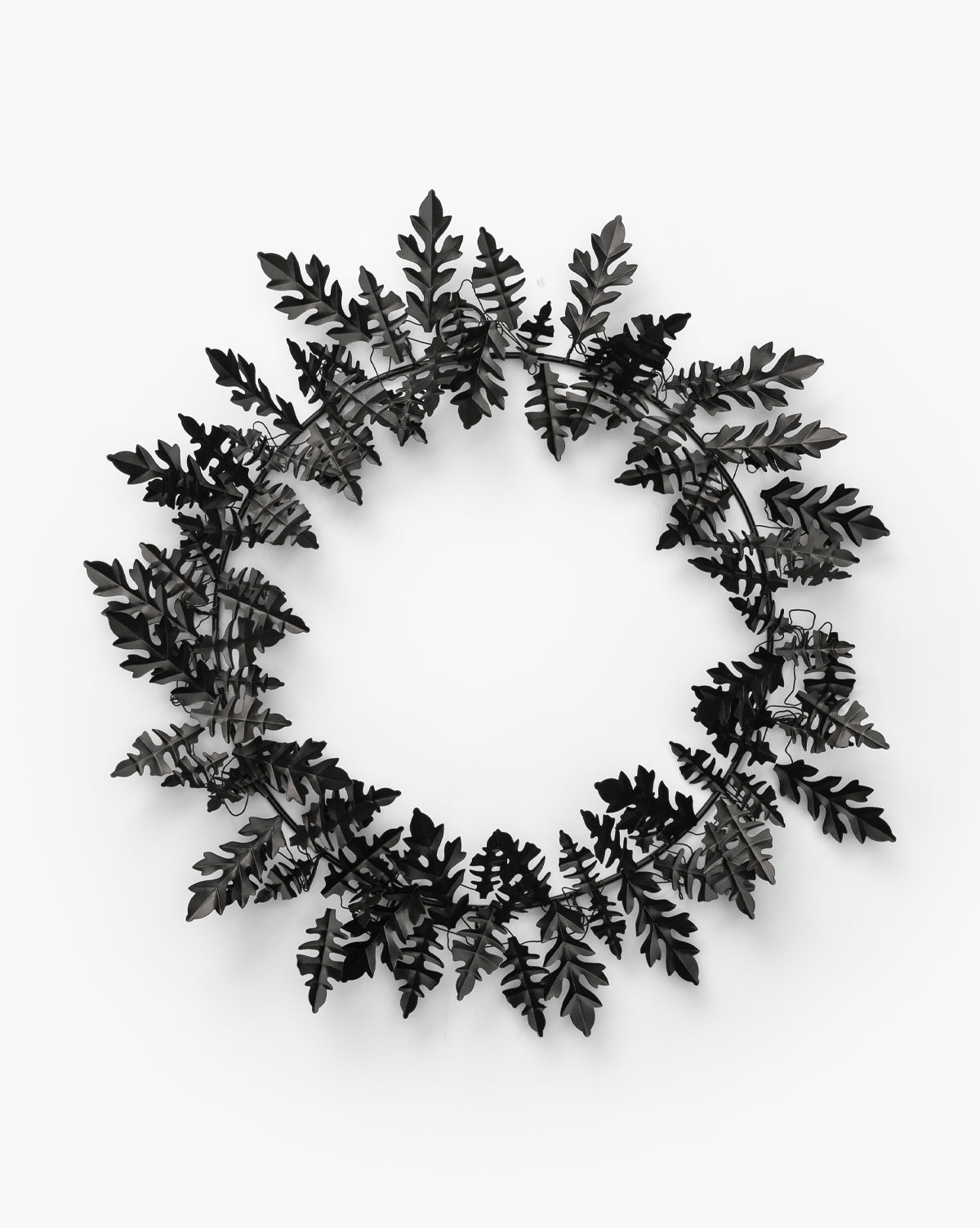 The Endora Metal Wreath features black metal oak leaves in a circular design, ideal for modern harvest styling or as bold seasonal décor, by McGee & Co. Shown here against a plain white background.