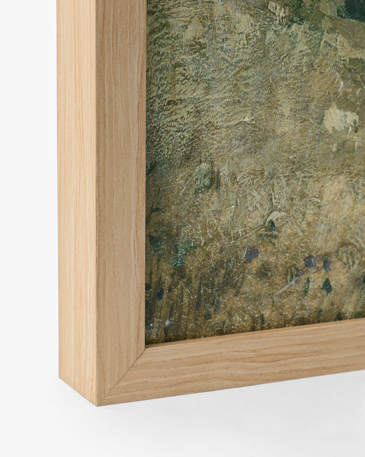 Close-up of the bottom left corner of a natural oak frame with visible wood grain, holding English Meadows, a textured greenish giclee on canvas. The frame features a light natural wood color, by McGee & Co.
