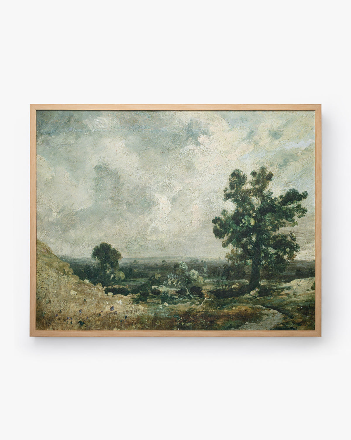 The English Meadows painting showcases a countryside landscape with a large tree, grassy fields, and a cloudy sky in muted tones, all set in a natural oak wood frame, by McGee & Co.