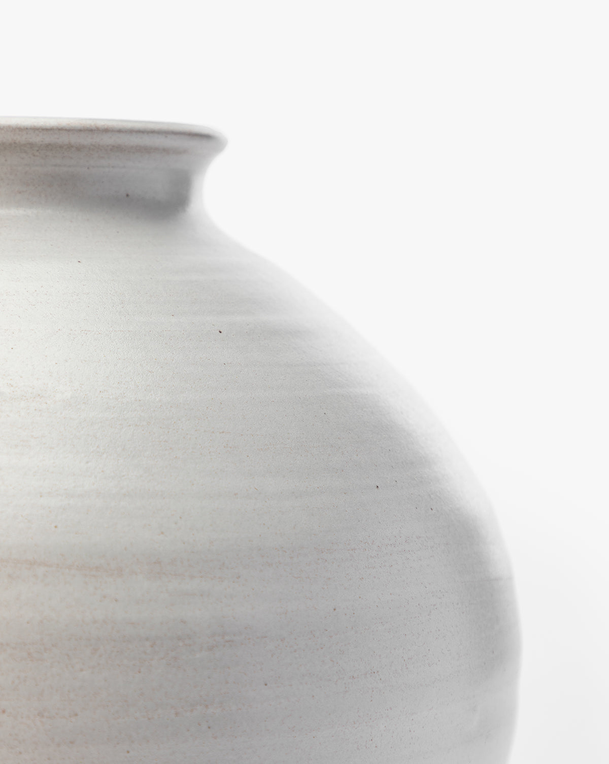 The Enola Vase is a smooth, light gray stoneware vase with a rounded body and narrow rim, finished with a subtle white glaze. Its minimalist design makes it perfect for modern home decor, shown here against a plain white background.