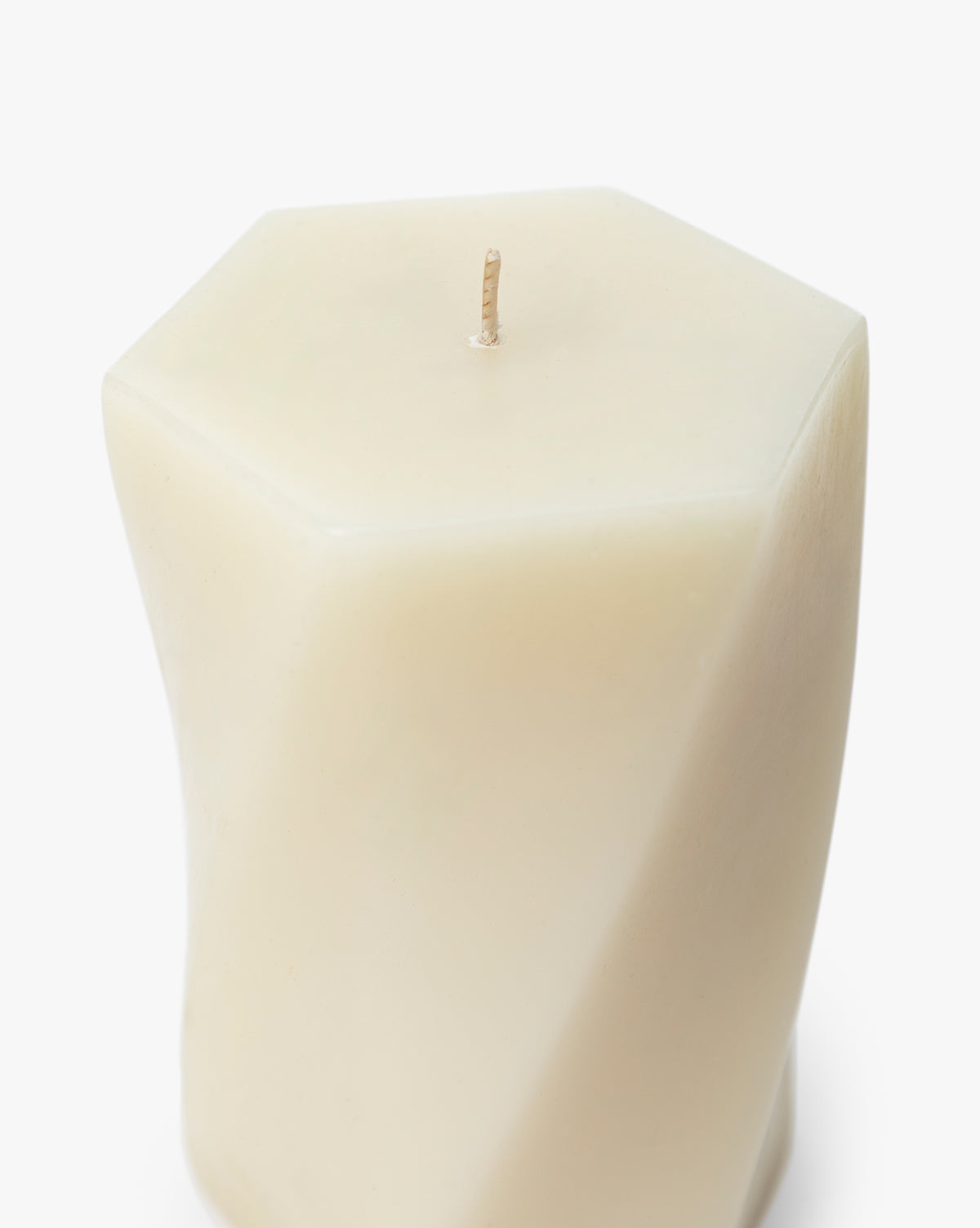 The Errol Wax Pillar Candle is a white, hexagon-shaped sculptural candle featuring a twisted design and single wick, set against a plain white background by McGee & Co.
