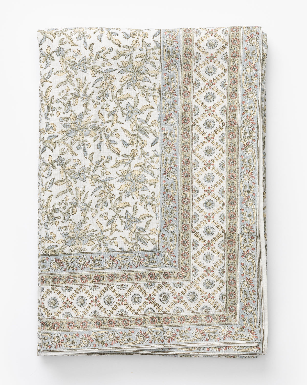 The Estelle Block Print Tablecloth is a folded linen-cotton piece featuring an intricate floral and geometric design in soft beige, blue, and pink on white, with a border of repeating diamond shapes and small flowers, by McGee & Co.