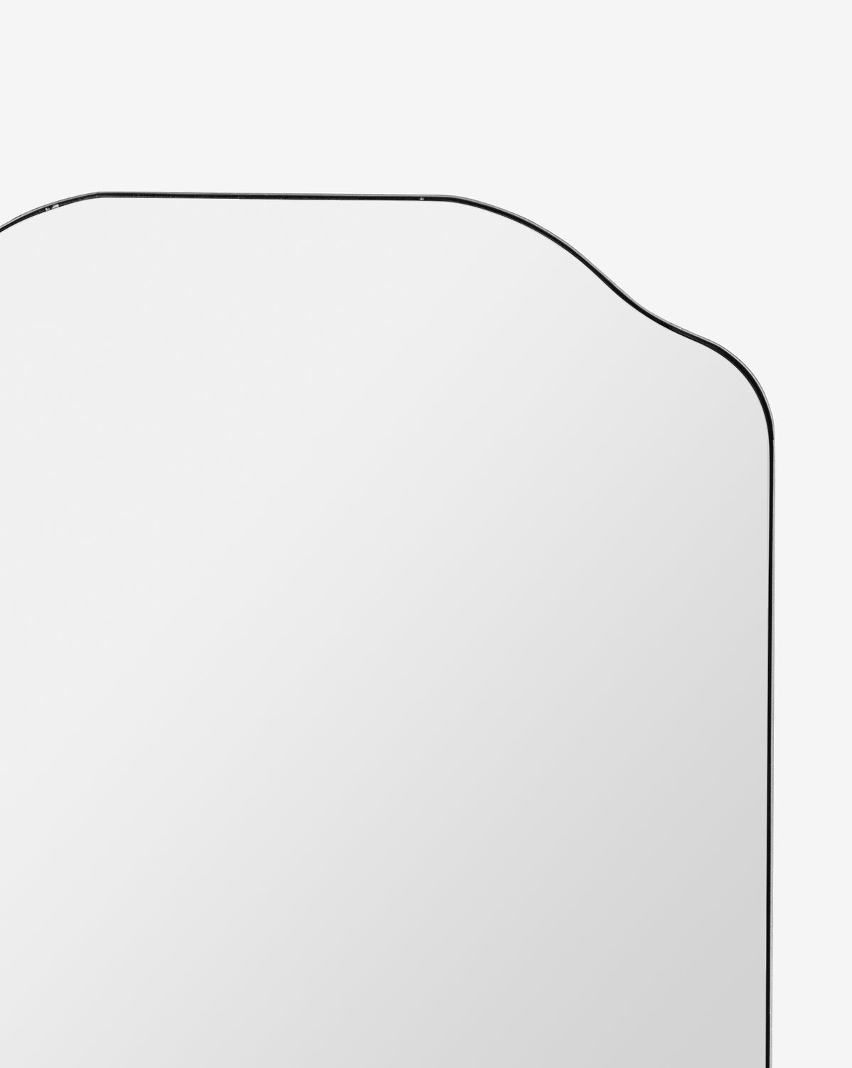 A close-up of the Ethel Wall Mirror’s upper section, featuring a metal frame with curved top corners, set against a plain white background, by McGee & Co.