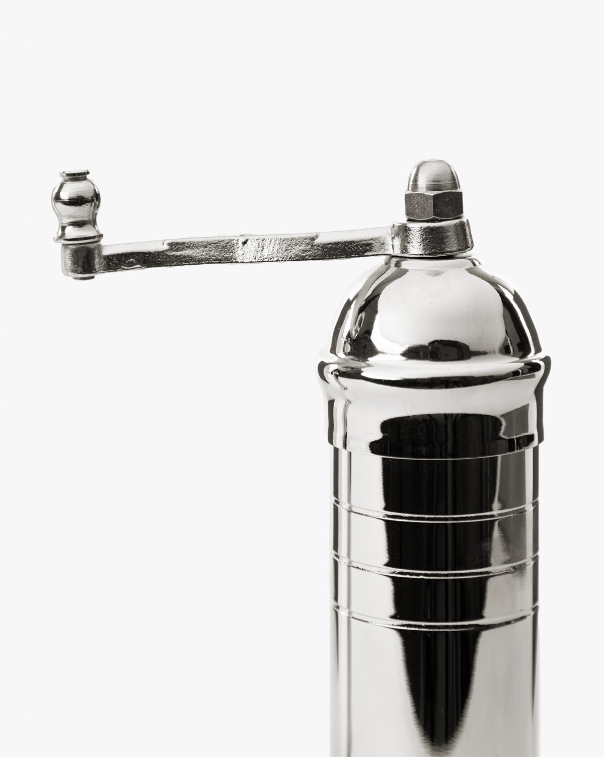 A close-up of the European Chrome Salt Mill features a shiny, metallic body, adjustable steel grinding mechanism, and a horizontal hand-crank handle on top, all set against a plain white background, by McGee & Co.