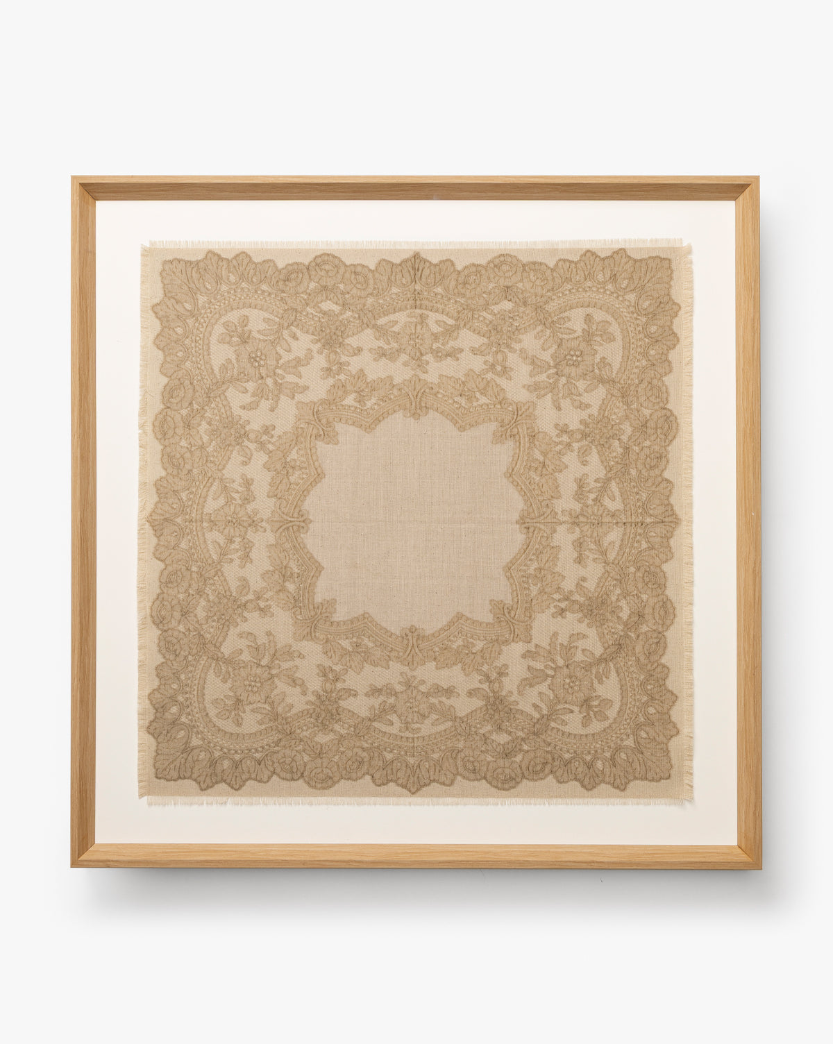 European Flare: Framed vintage lace handkerchief featuring detailed floral and leaf designs on white, bordered by a natural woodgrain frame for timeless European elegance, by McGee & Co.
