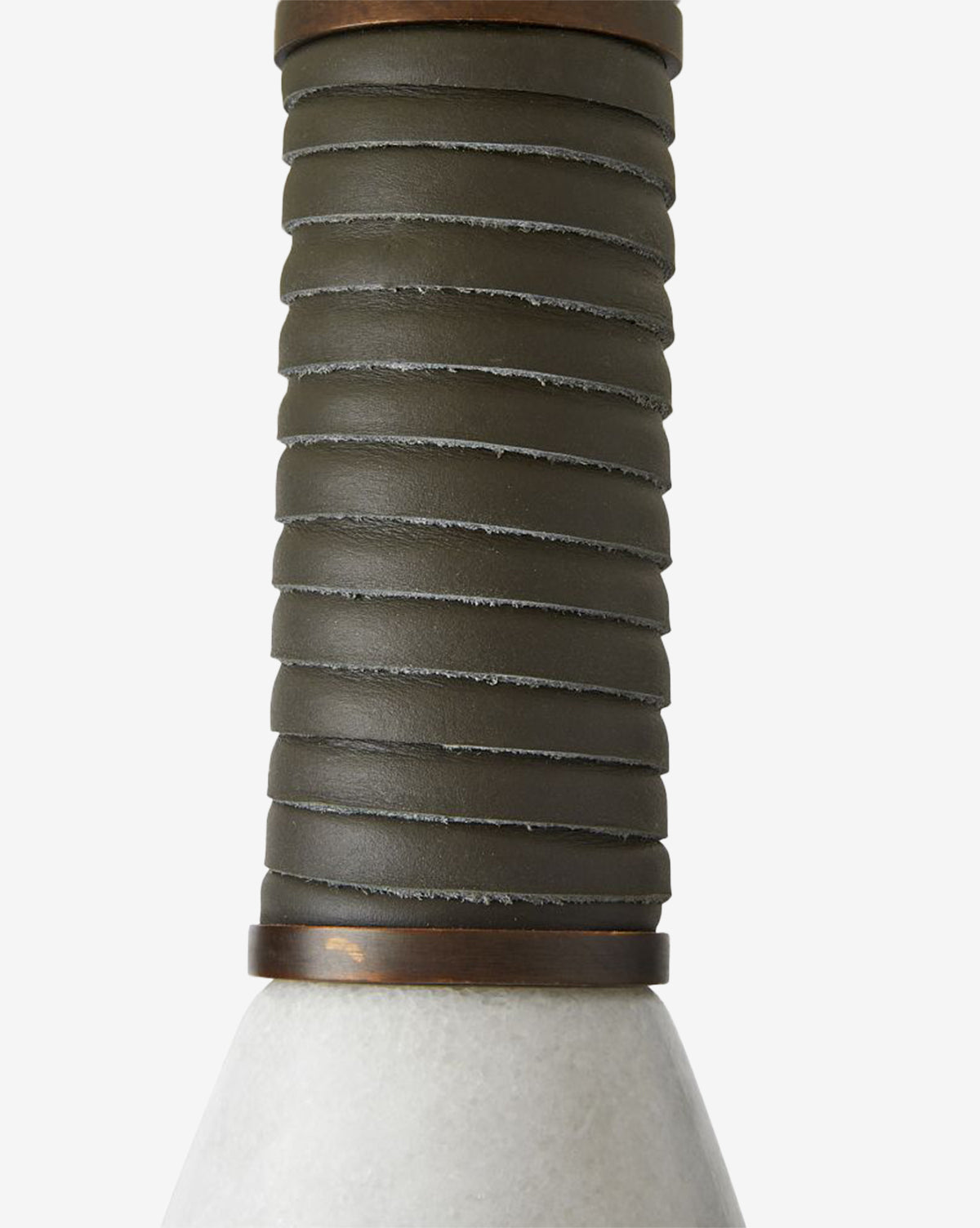 Close-up of the Everly Table Lamp’s dark, ribbed leather-wrapped handle attached to a smooth, conical white marble base. The image focuses on the unique texture and design details of the lamp’s handle, by McGee & Co.
