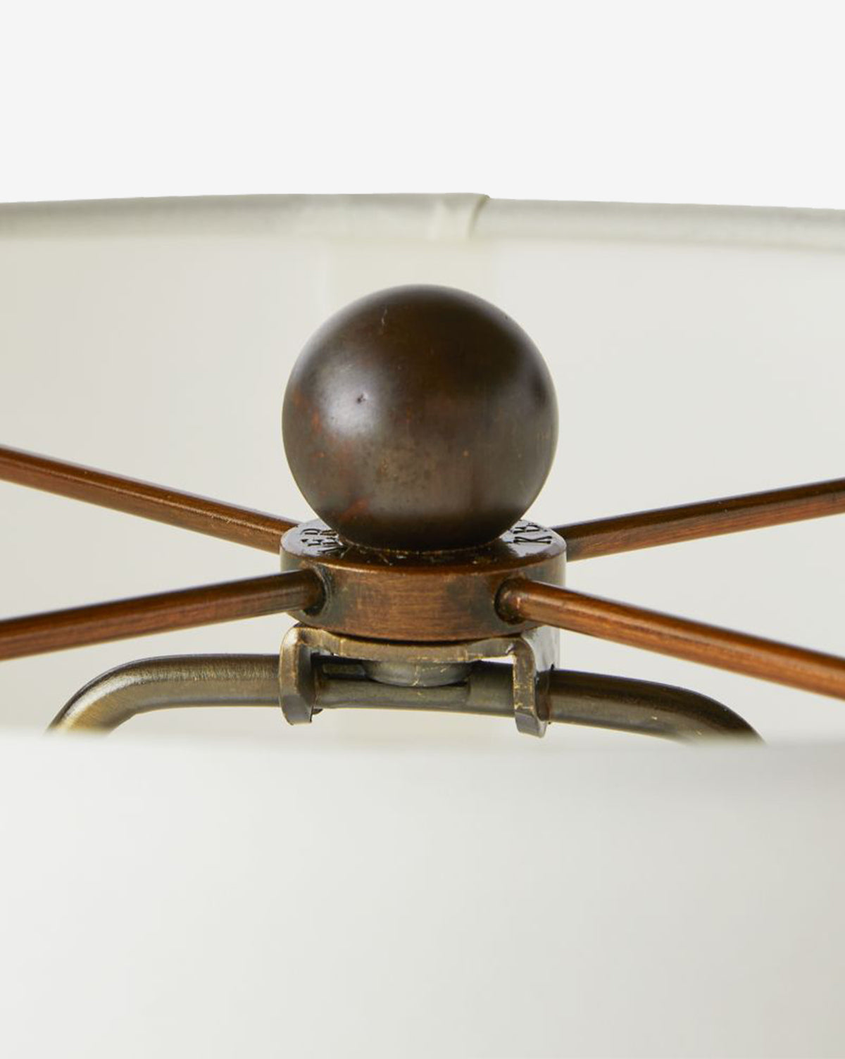 Close-up of the Everly Table Lamps metal fixture with a round dark finial and metal rods joining an ivory microfiber shade, by McGee & Co.