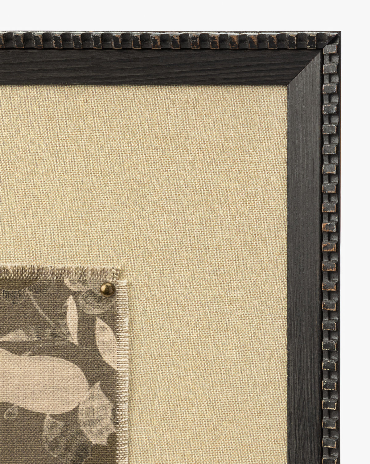 A close-up of the Fable textural art piece on beige fabric in a dark wooden frame, with a pinned fabric swatch featuring a neutral leaf and floral design by McGee & Co.