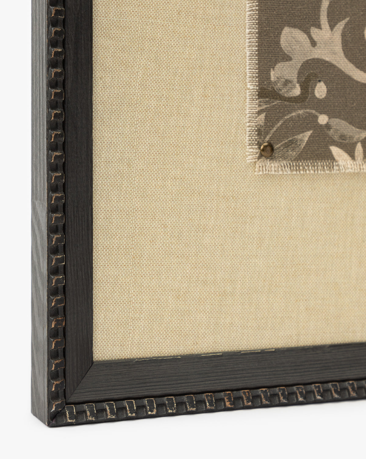 Close-up of Fable, a textural art piece with a dark decorative black frame, beige fabric background, and a small patterned fabric swatch pinned to the right by McGee & Co.