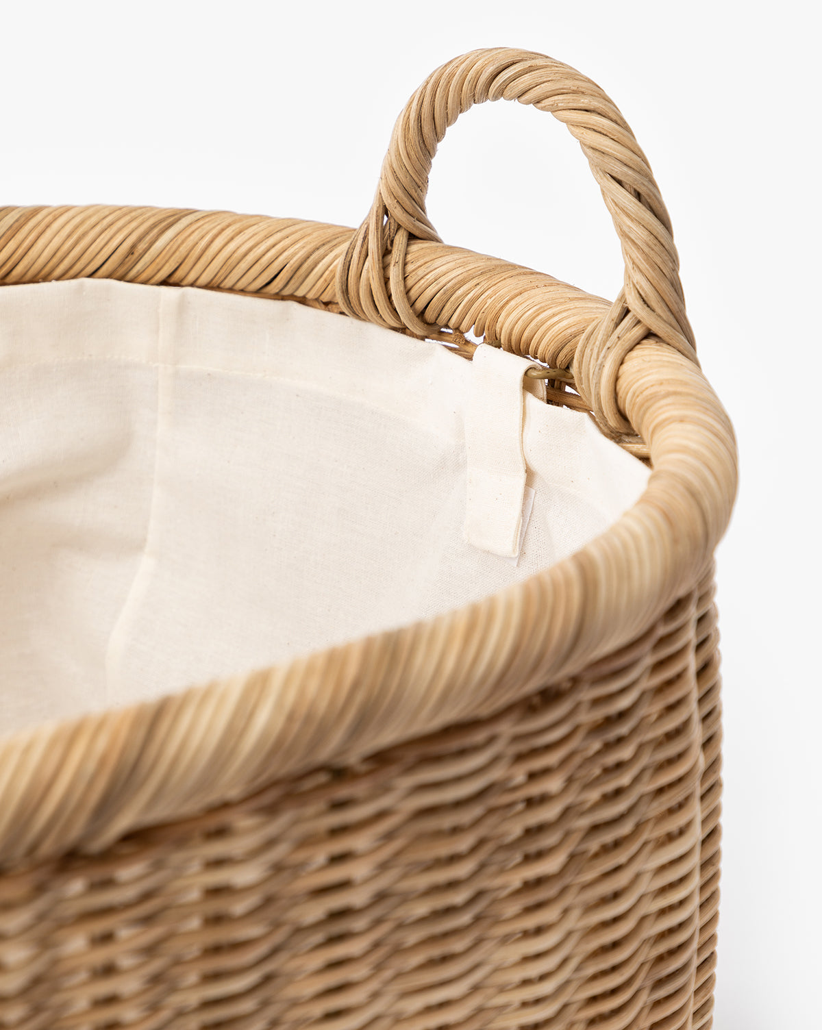 Close-up of the Fairway Laundry Basket, featuring a circular wicker design, sturdy handle, and soft canvas lining. Partly filled and set against a plain white background, by McGee & Co.