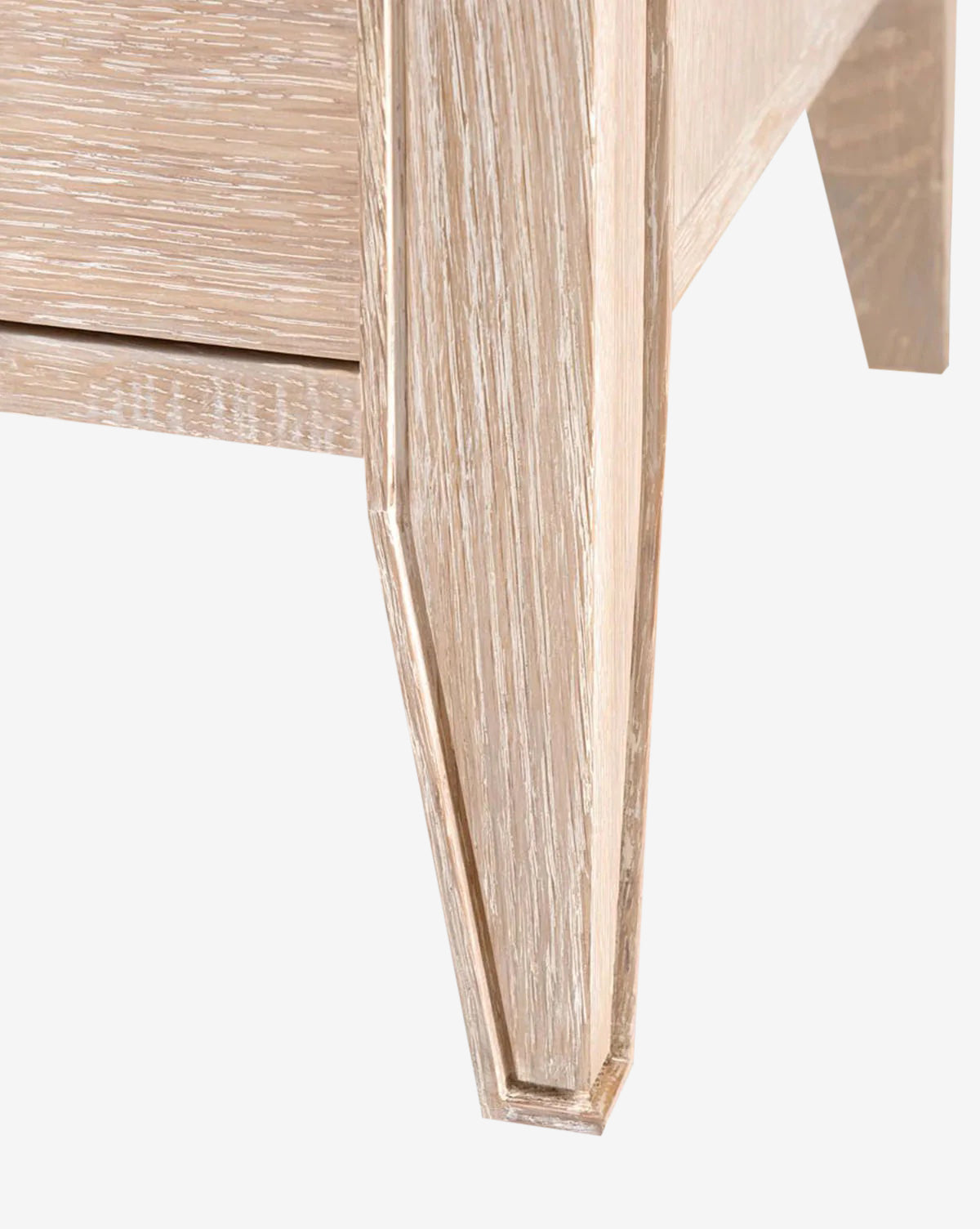 Close-up of a Falkner Dresser leg shows its light natural wood finish and visible grain. The angular, geometric design connects seamlessly to a matching panel, highlighting the French-inspired elegance of the Falkner Dresser.