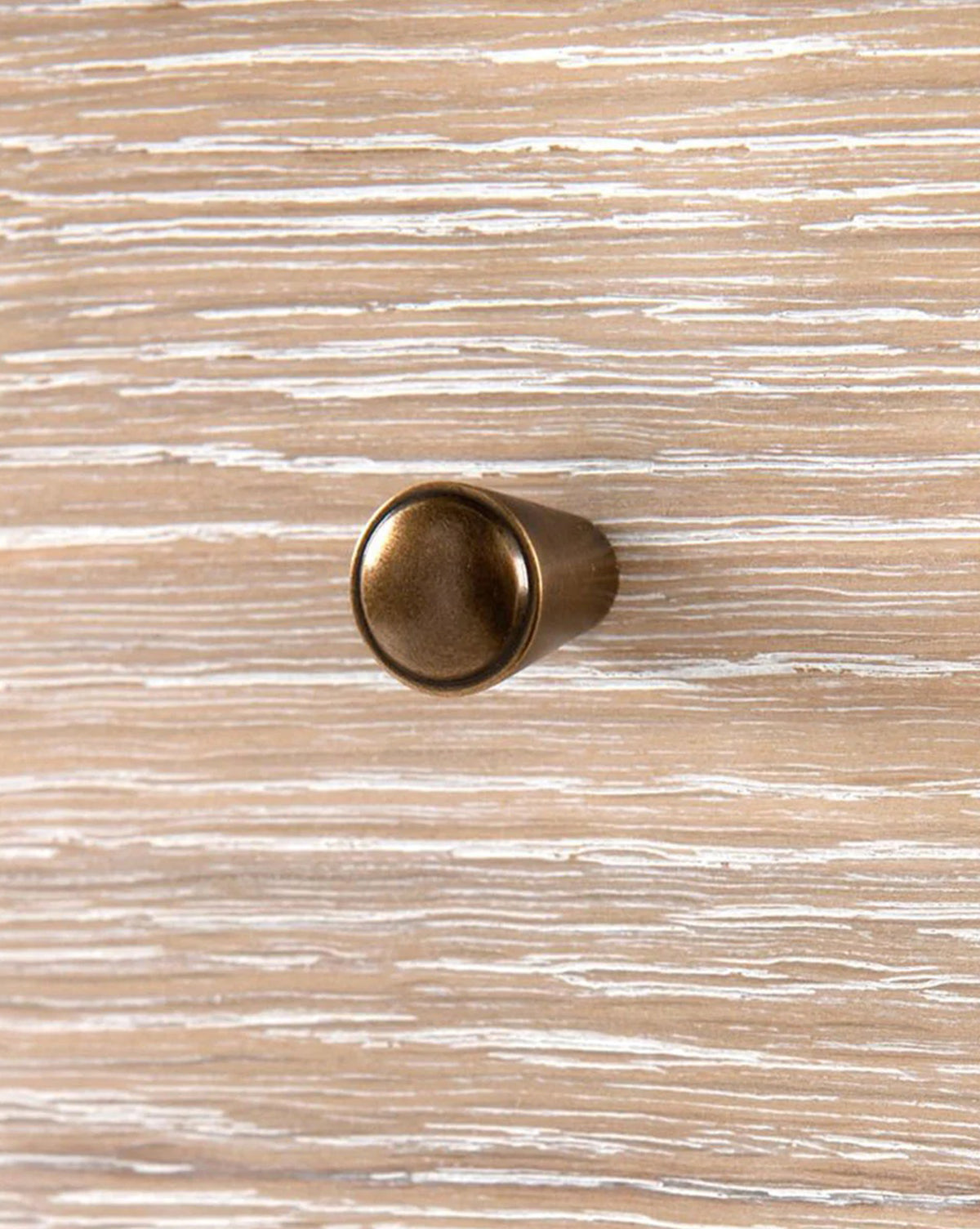 A round, bronze-colored drawer knob is attached to the light brown and white textured surface of the Falkner Dresser, adding elegant detail to its French-inspired design.