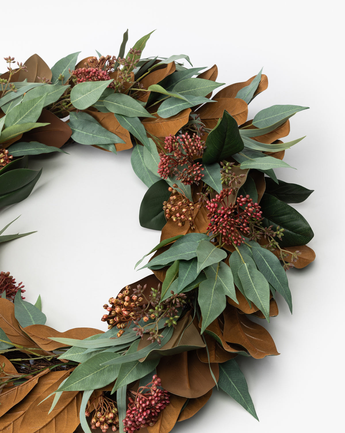 A close-up of the 30 Faux Magnolia & Eucalyptus Wreath, featuring green and brown leaves with red berry accents, displayed against a plain white background.