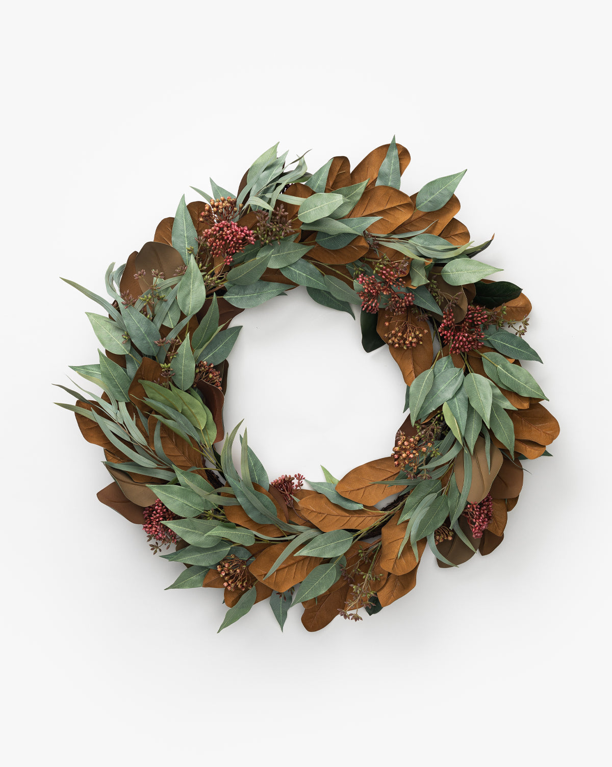 The 30 Faux Magnolia & Eucalyptus Wreath features lifelike magnolia and green eucalyptus leaves with red berry clusters, artfully arranged in a circle against a white background for a decorative winter touch.