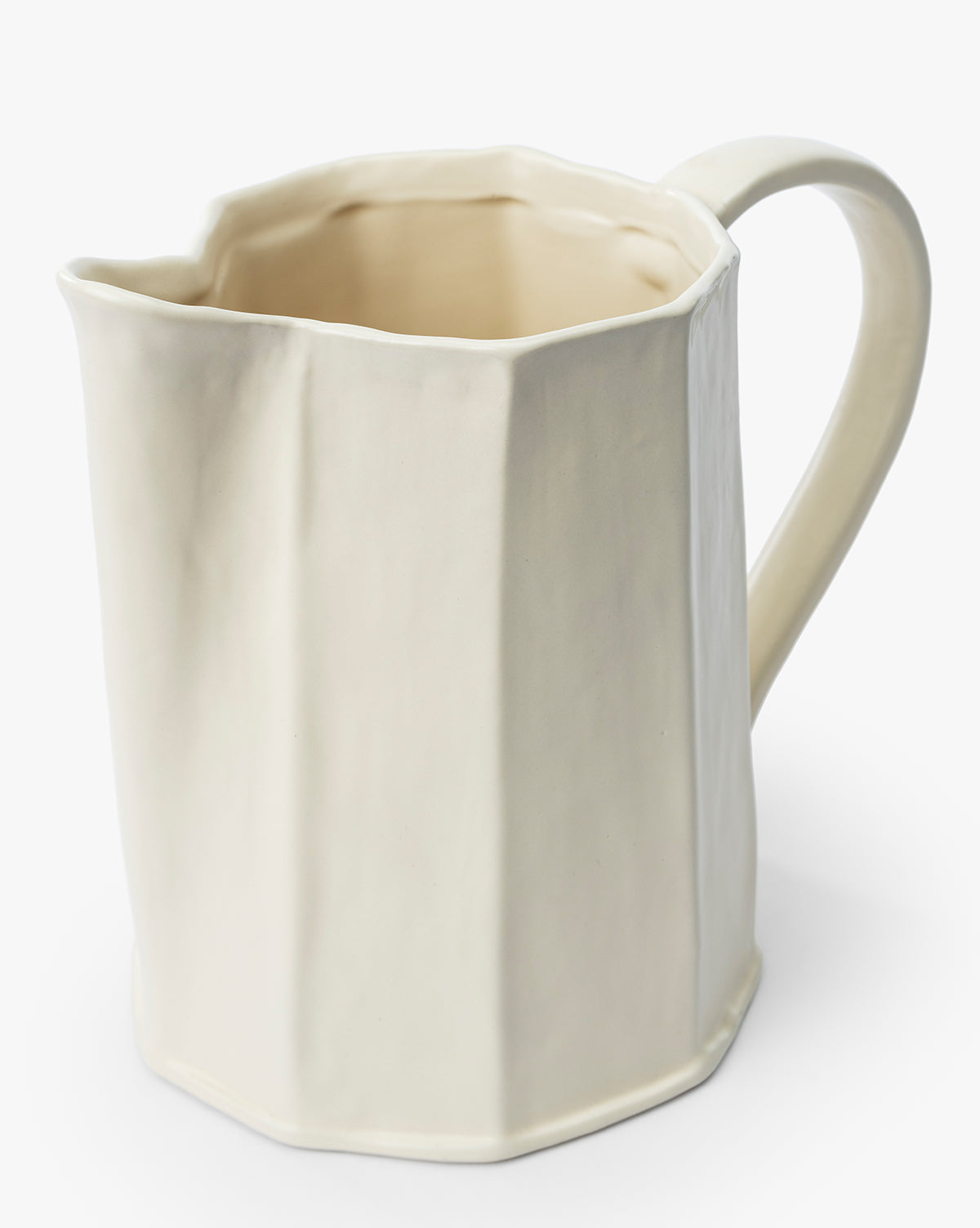 The Fielding Ceramic Pitcher is a cream-colored stoneware piece with a faceted, angular design and curved handle, ideal for rustic kitchen decor, photographed against a plain white background by McGee & Co.