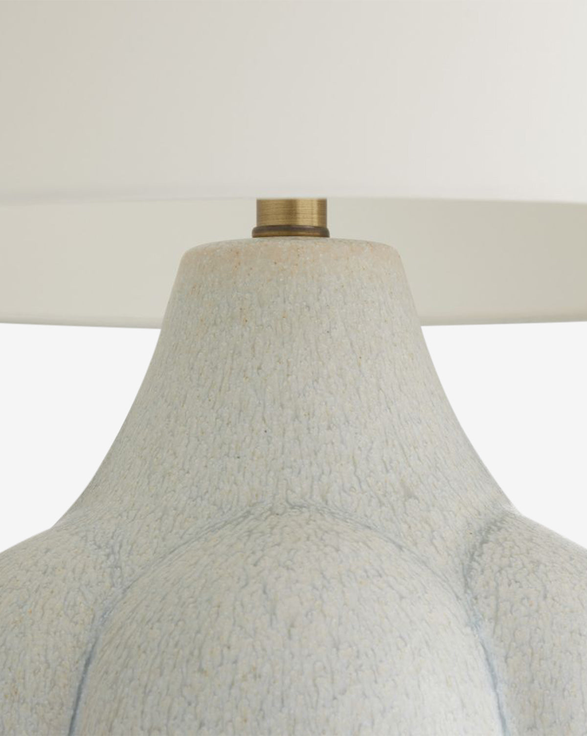 Close-up of the Fig Table Lamp, featuring a grooved ceramic base, white lampshade, and antique brass fitting. The textured design brings elegant decor appeal, shown against a plain white background by McGee & Co.
