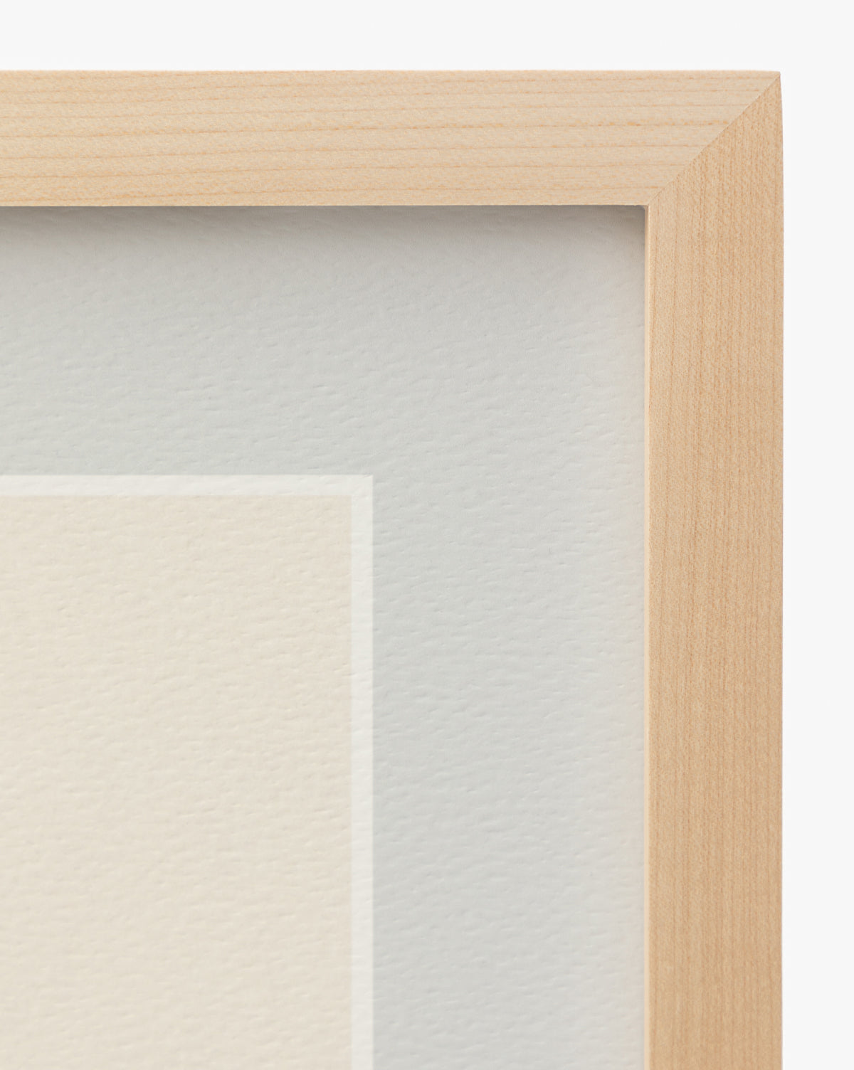 Close-up of the top right corner of the Finn wooden picture frame with light wood grain, part of a white mat, and textured Scottish Terrier sketch wall art beneath glass by McGee & Co.