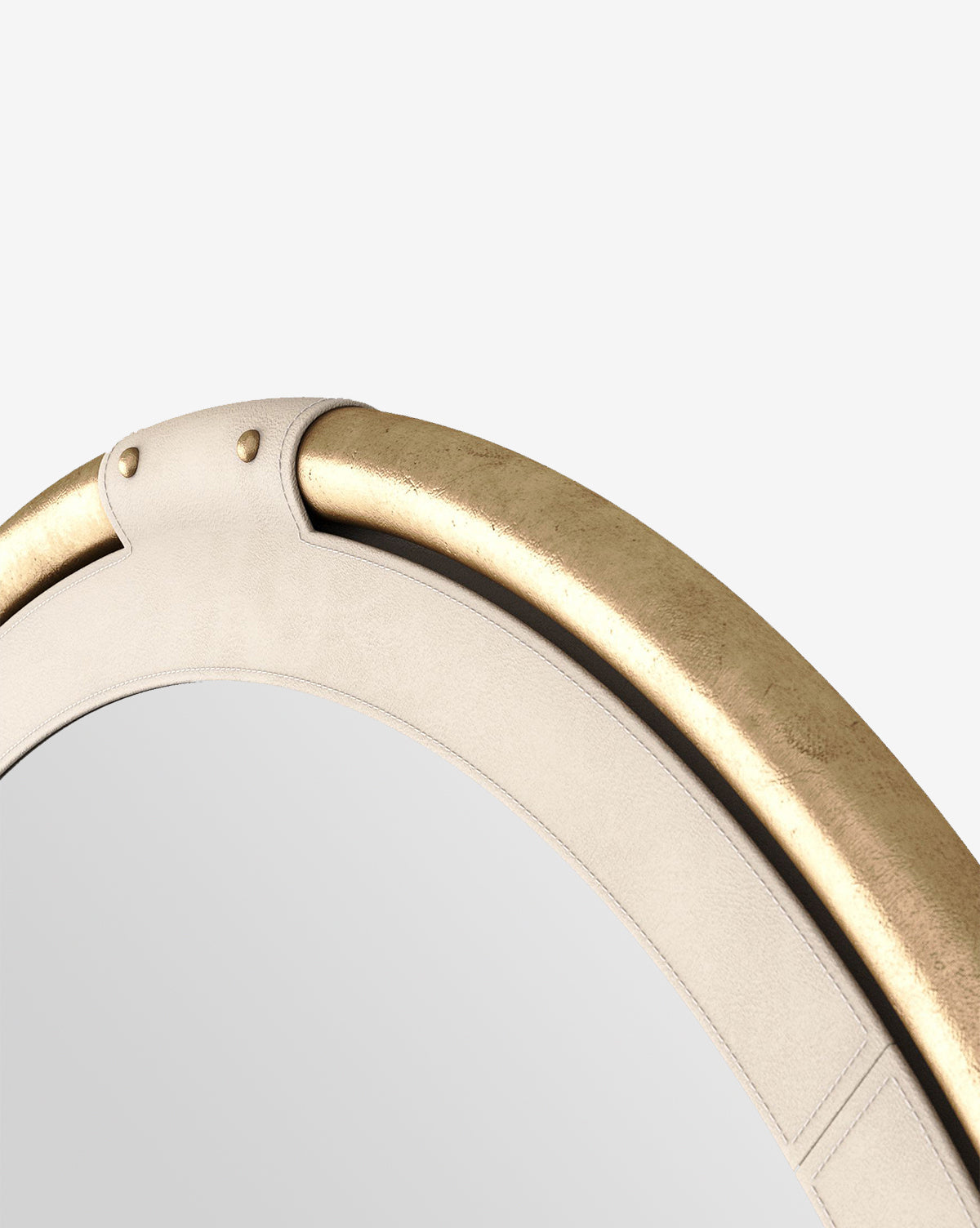 Close-up of the Flora Mirror’s top, featuring a beige leather border with antique brass trim, decorative stitching, and metal rivets, all set against a plain white background by McGee & Co.