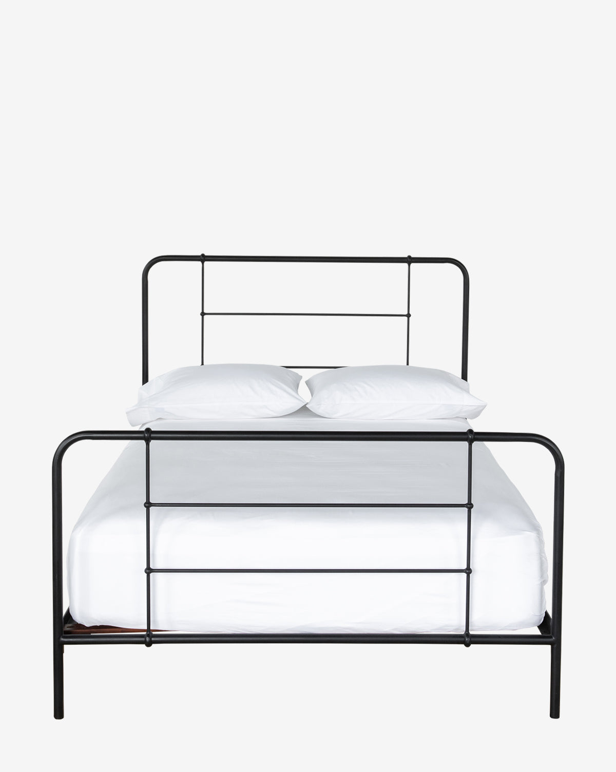 The Floyd Iron Bed, featuring a matte black minimalist design, is displayed with white bedding and two white pillows against a plain white background, by McGee & Co.