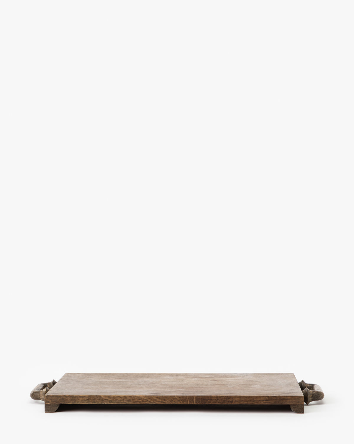 The Fordham Board is a rectangular solid oak wood serving tray with short legs and handles, ideal for serving charcuterie, displayed on a white background, by McGee & Co.