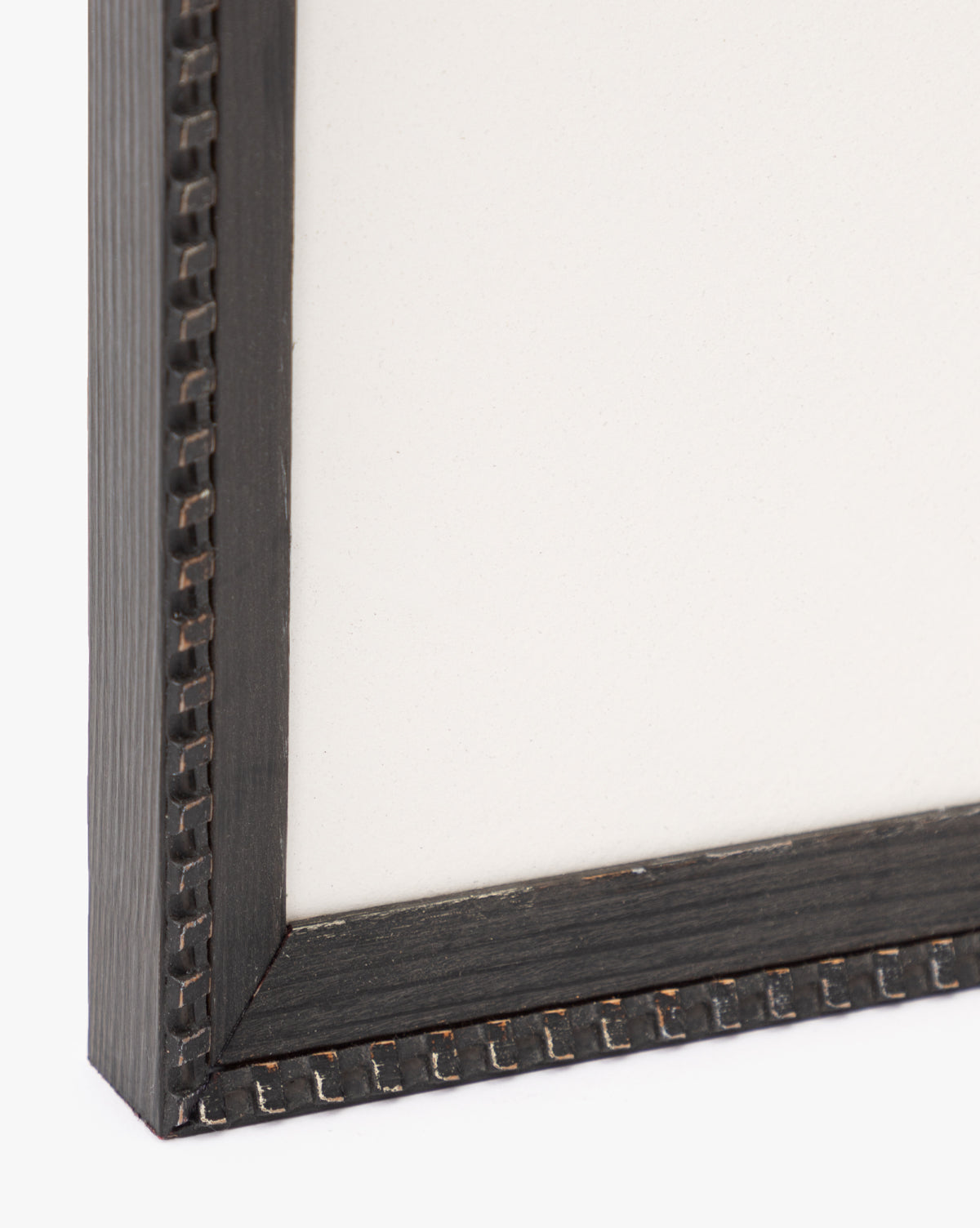 Close-up of the bottom left corner of a black wood frame with a decorative pattern, showcasing the Forest Meadow print on textured fine art paper inside.