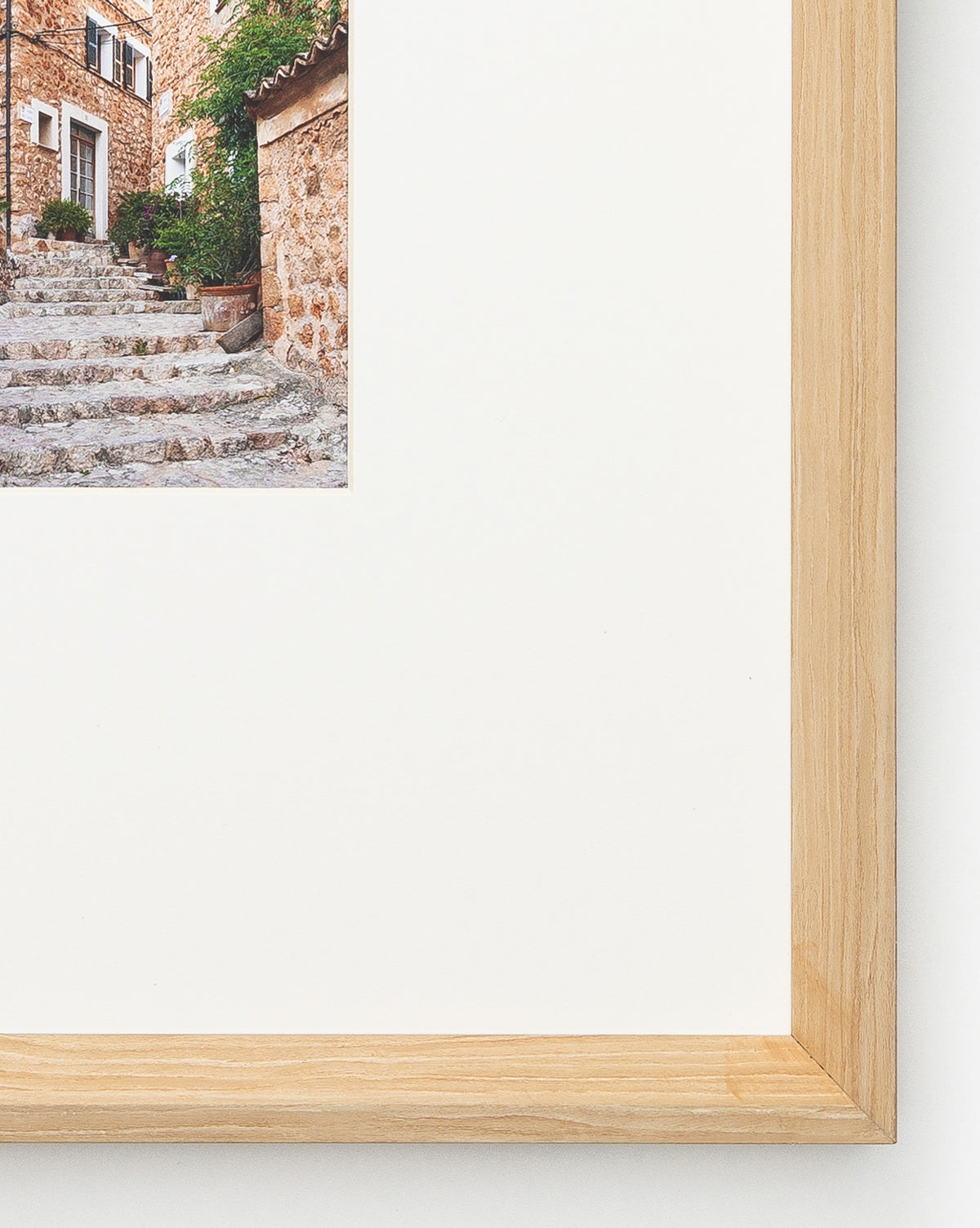 Close-up of the Fornalutx frame, showcasing natural woodgrain and highlighting a photo of stone steps by a rustic building with potted plants. Most of the Fornalutx frame is visible, emphasizing its thoughtful design and composition.
