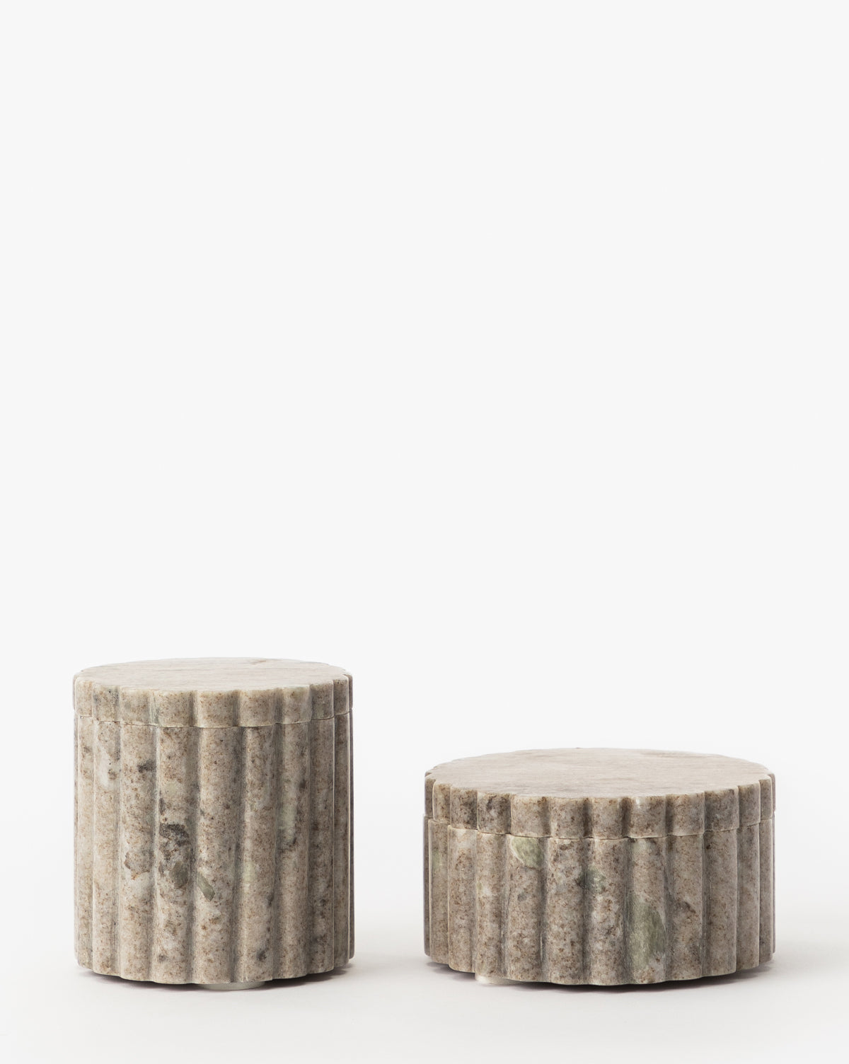 A duo of Forster Marble Canisters with vertical grooves and a weathered look rest on a white background; one is taller than the other, creating striking home accents crafted from natural marble.