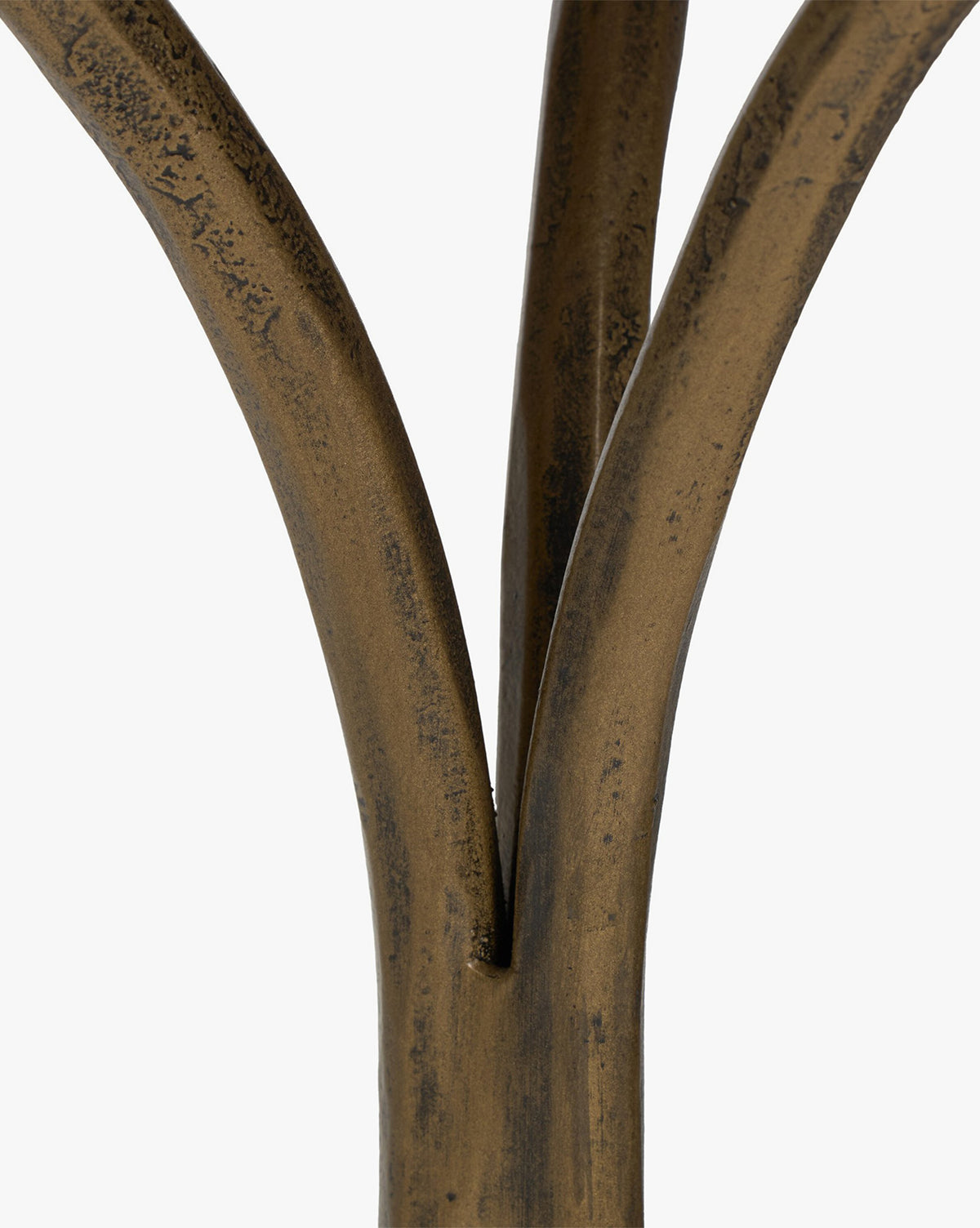 Close-up of three bronze-colored, slightly curved metal rods converging at the base, highlighting the hammered aged brass detail of the Fossil Marble End Table against a plain white background, by McGee & Co.