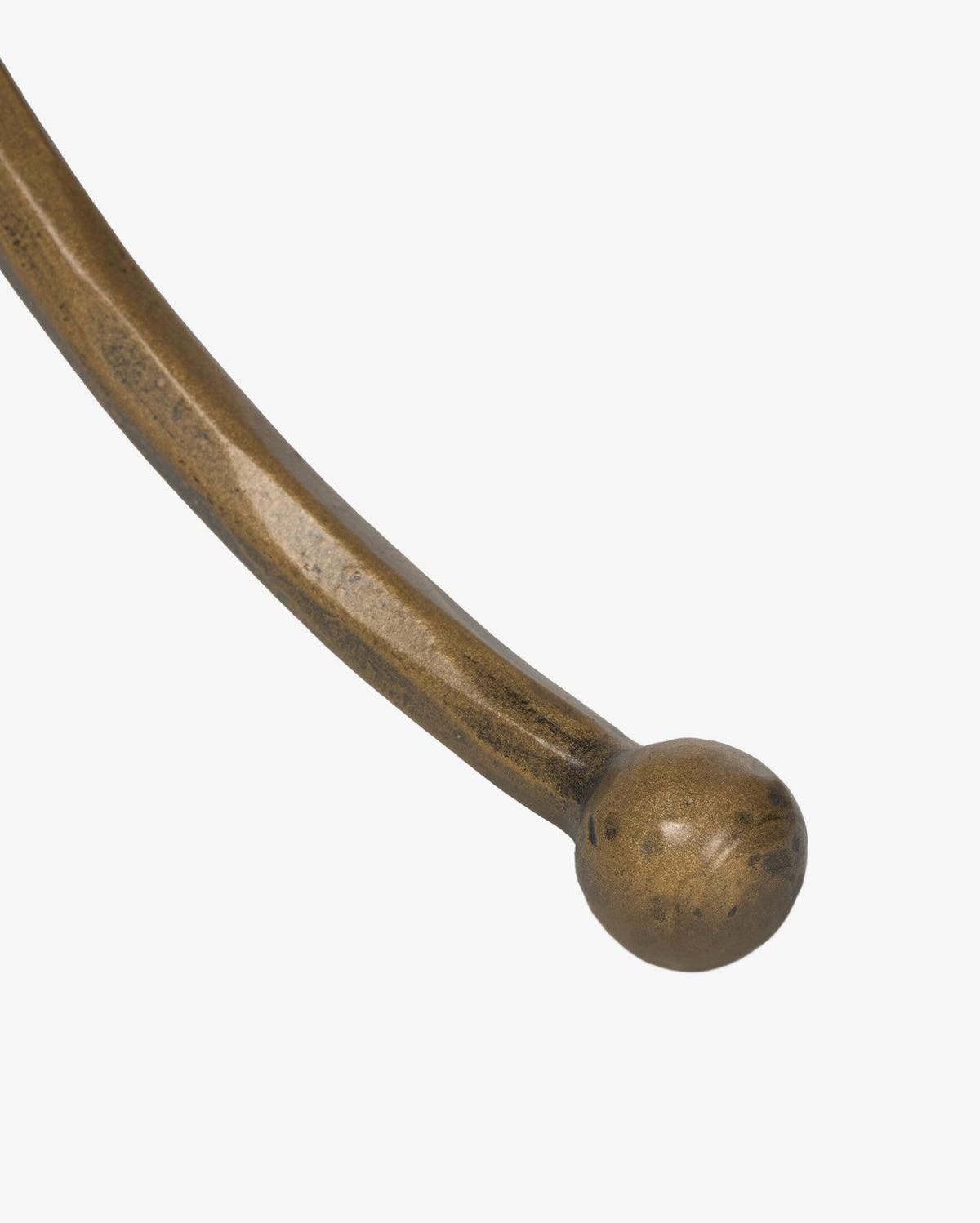 A close-up of the Fossil Marble End Tables curved, hammered aged brass metal leg ending in a round ball, set against a plain white background, by McGee & Co.