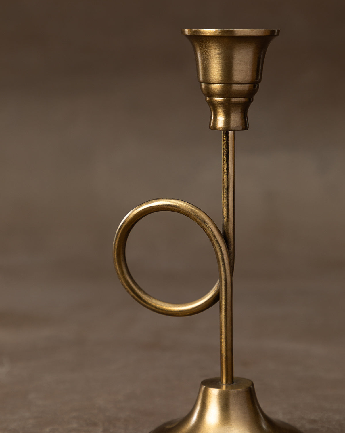 The French Horn Taper Holder, crafted from brass with a circular loop stem detail, is ideal for holiday styling and displayed on a simple light background, by McGee & Co.