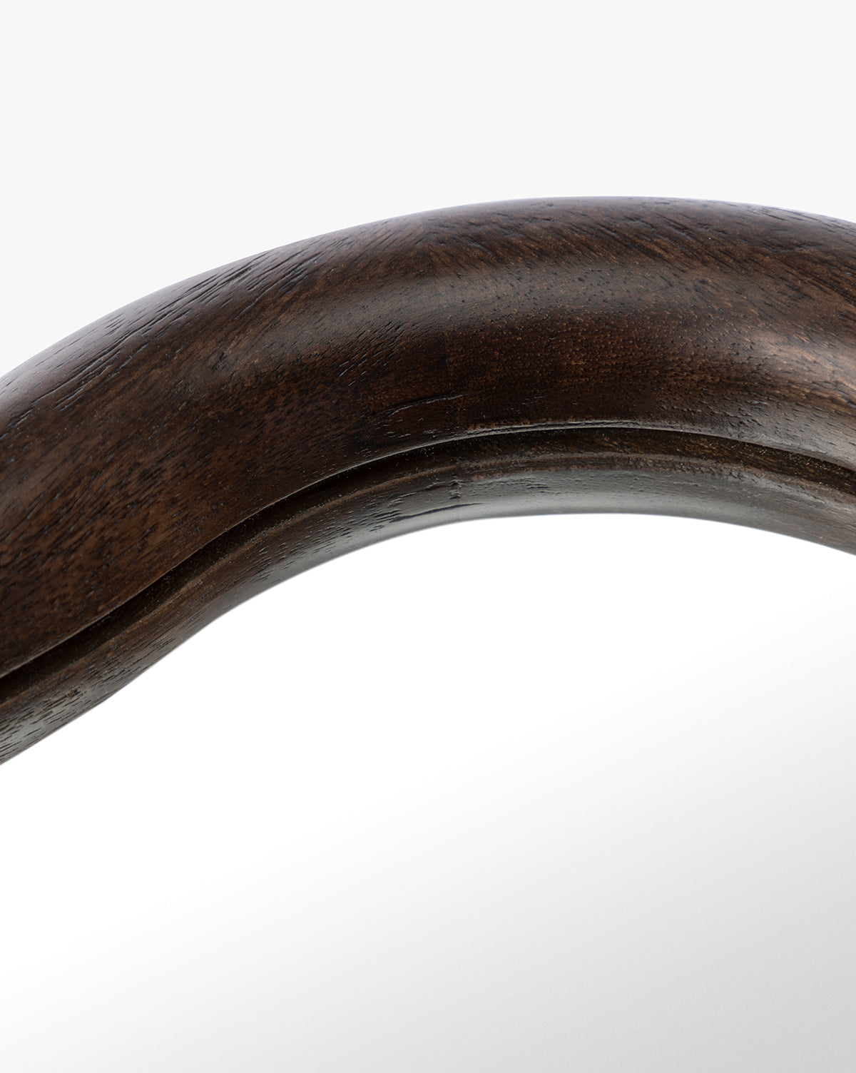 Close-up of the Freya Shelf Mirror featuring a dark polished wooden frame with a curved edge that reflects light on its smooth surface—an ideal accent for entryway decor, by McGee & Co.