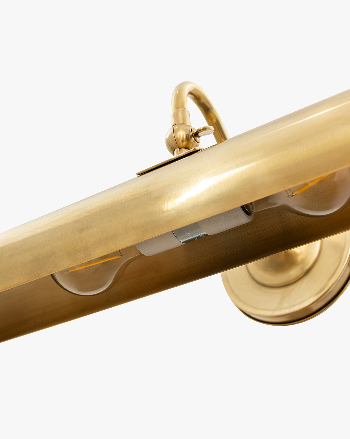 Close-up of the Gallery Picture Sconce, featuring a vintage-inspired cylindrical brass design with a burnished bronze finish. The image displays part of the bulb and mounting plate set against a white background, by McGee & Co.