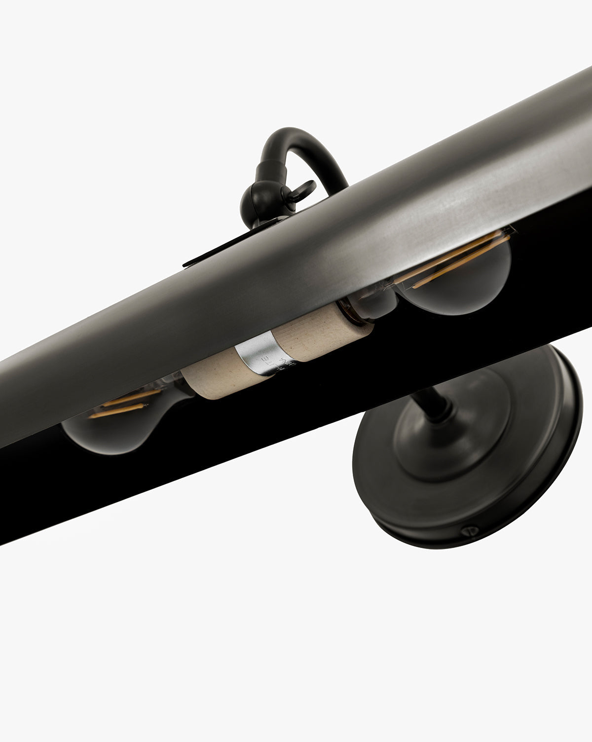 Close-up of the Gallery Picture Sconce, a vintage-inspired black metal light with two exposed bulbs and a round base, shown from a low angle against a white background, by McGee & Co.