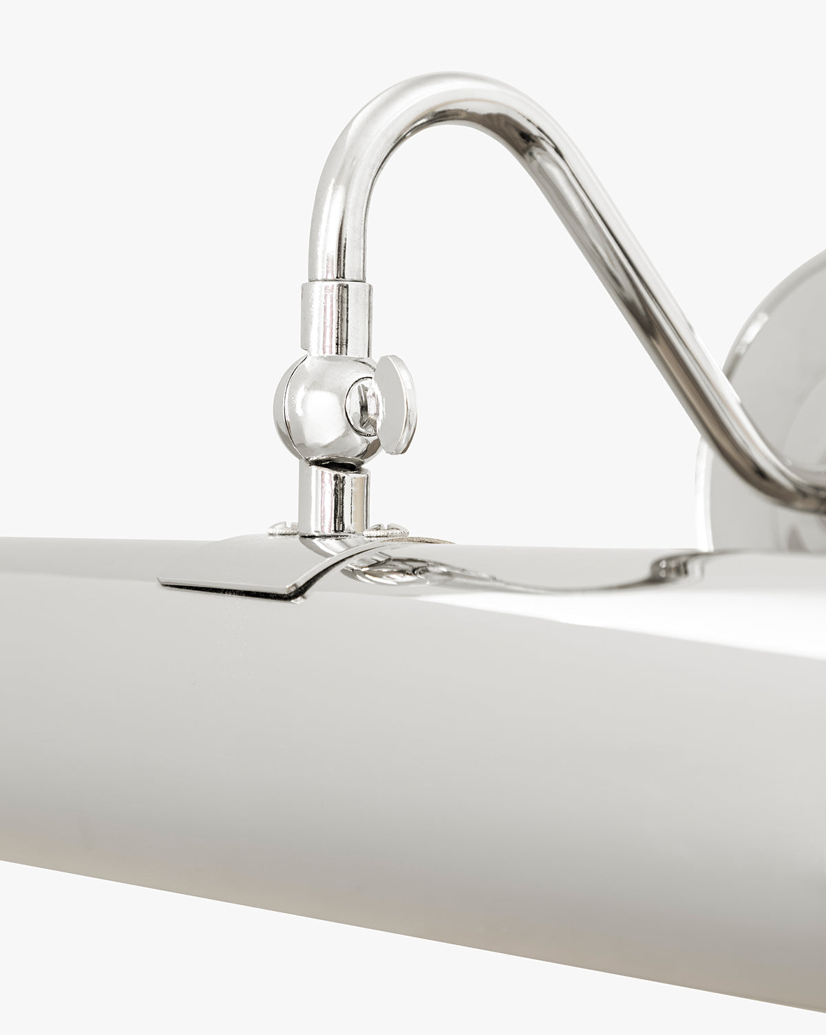 Close-up of the Gallery Picture Sconce, featuring a curved arm and cylindrical shade in burnished bronze, mounted on a plain white wall by McGee & Co.