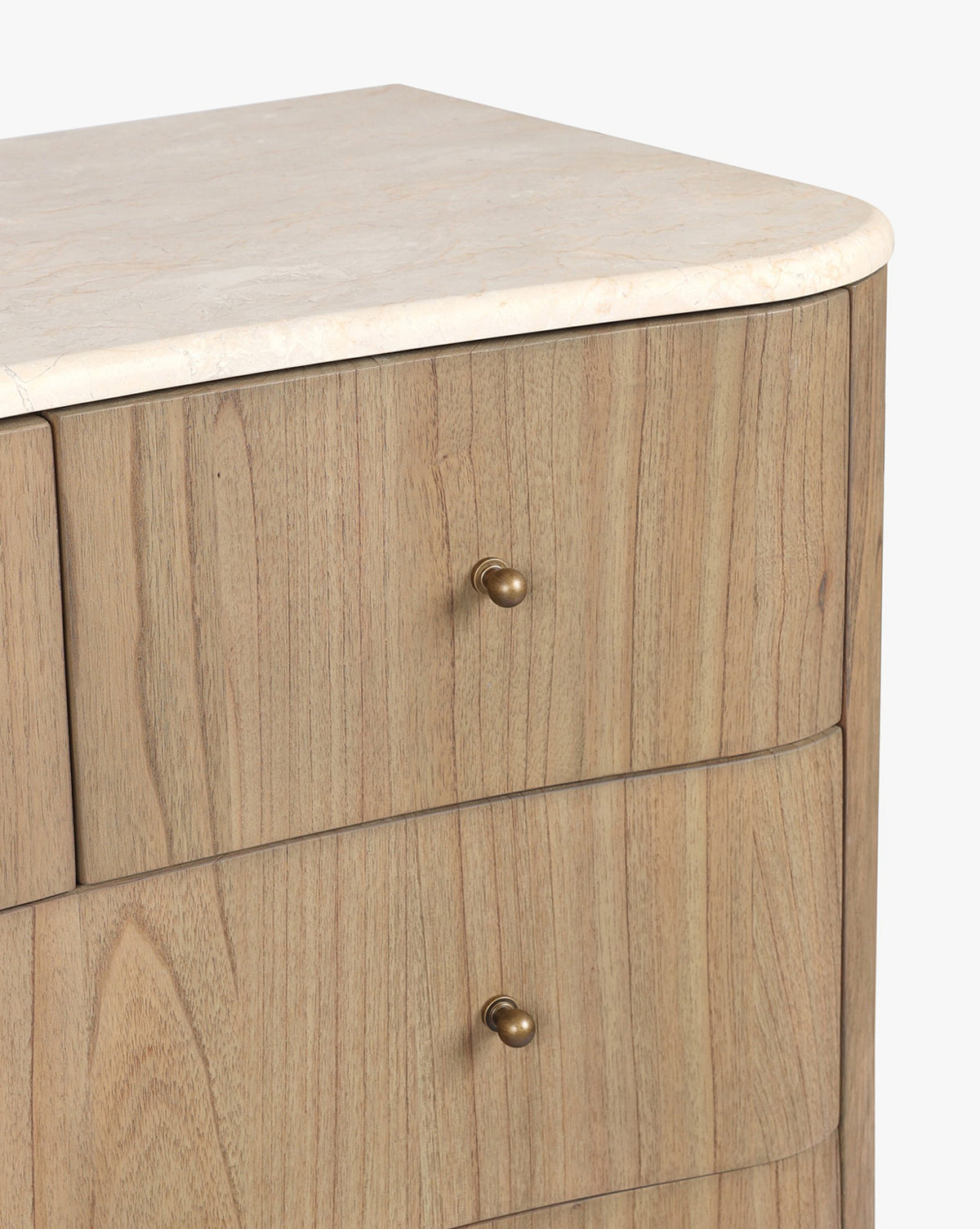 A close-up of the Gatlin Chest, made of solid mindi wood, features a light stone top, three roomy drawers with round brass knobs, a natural light grain finish, and smoothly rounded corners by McGee & Co.